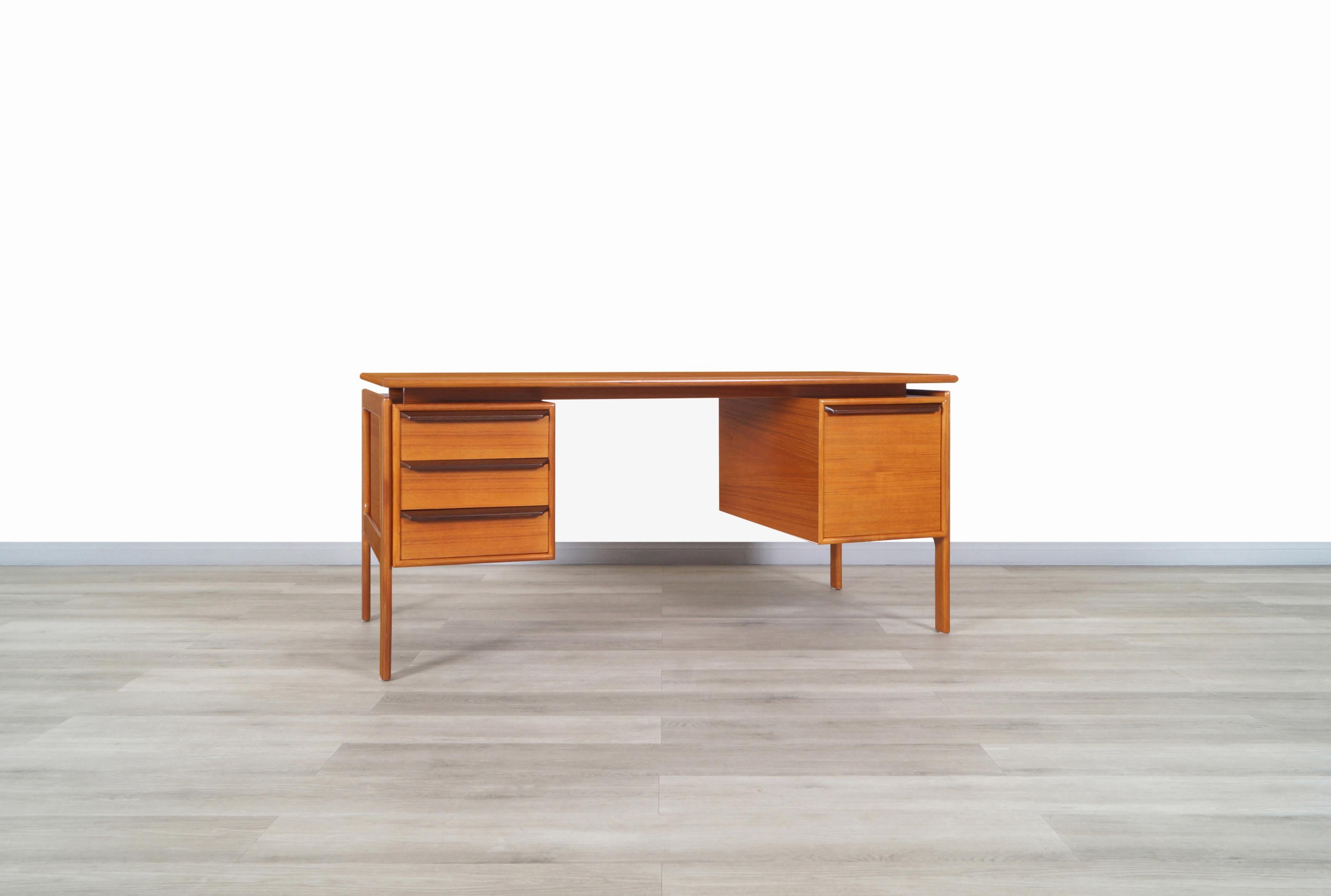 Stunning Danish modern floating top teak desk manufactured by G.V. Møbler in Denmark, circa 1960s. On the left side features three dovetail drawers, and on the right side, it has a wide file drawer with aluminum rails that facilitate the sliding of