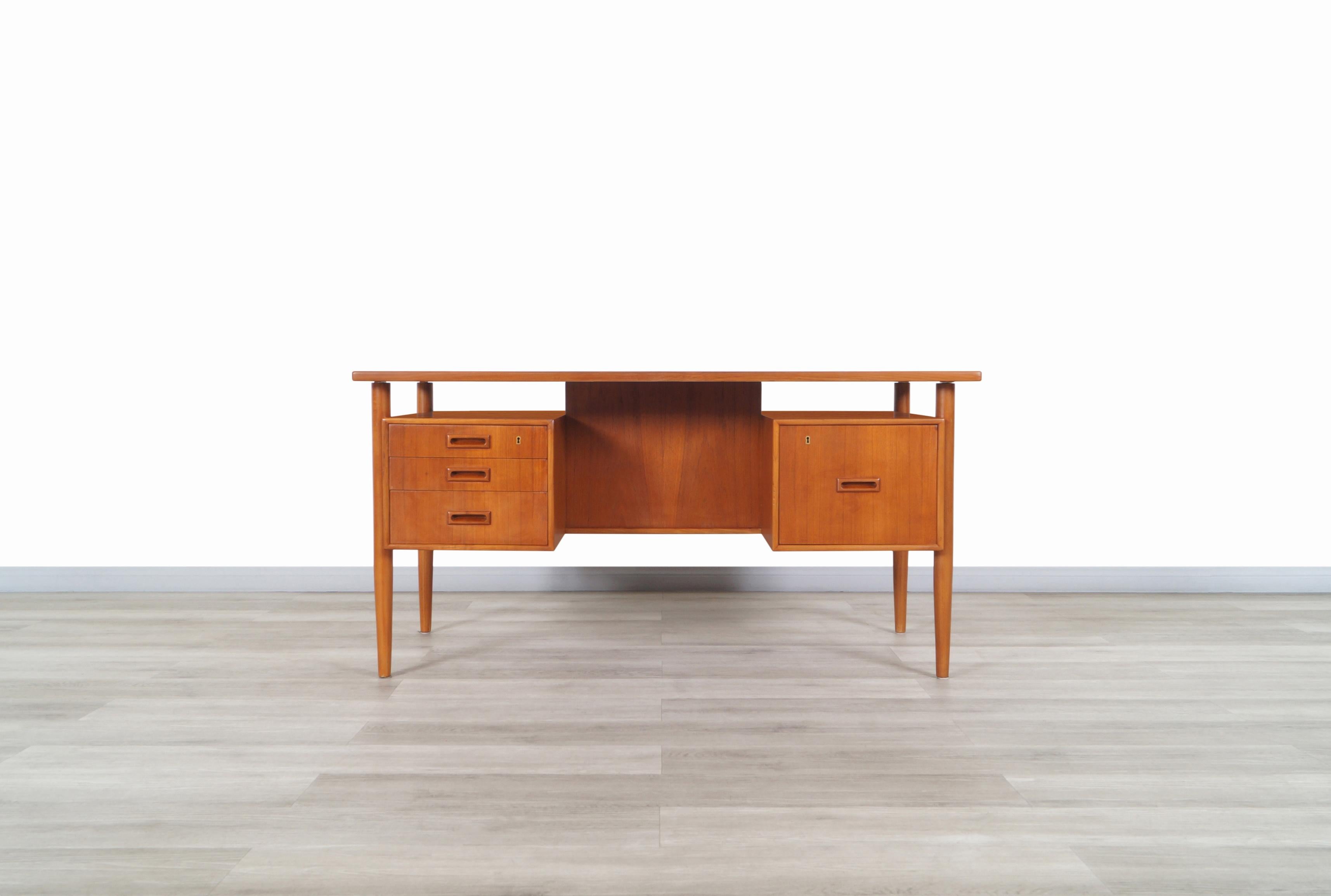 Amazing Danish modern floating top teak desk by Johannes Sorth for Bornholm Møbelfabrik in Denmark, circa 1960s. Features a total of four dovetail drawers, which the right drawer is a file drawer that will be quite useful for storing your documents.