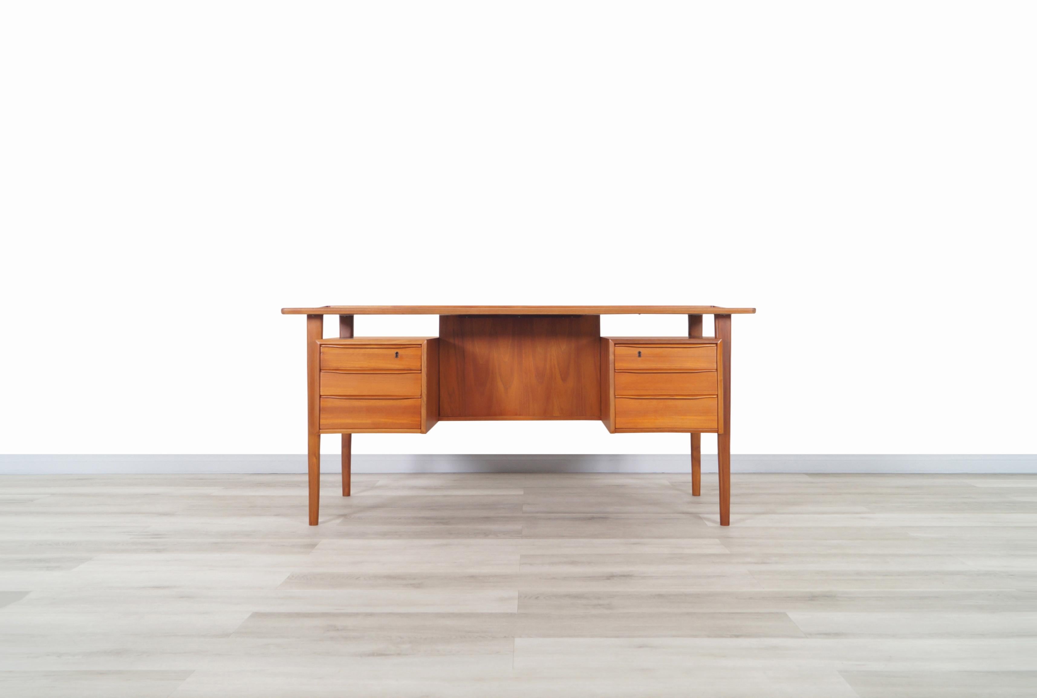 A stunning Danish modern teak desk designed by Peter Løvig Nielsen for Løvig Dansk in Denmark, circa 1960s. Features a floating top design with a raised lip along the edges and includes three dovetailed drawers on each side, all integrated with