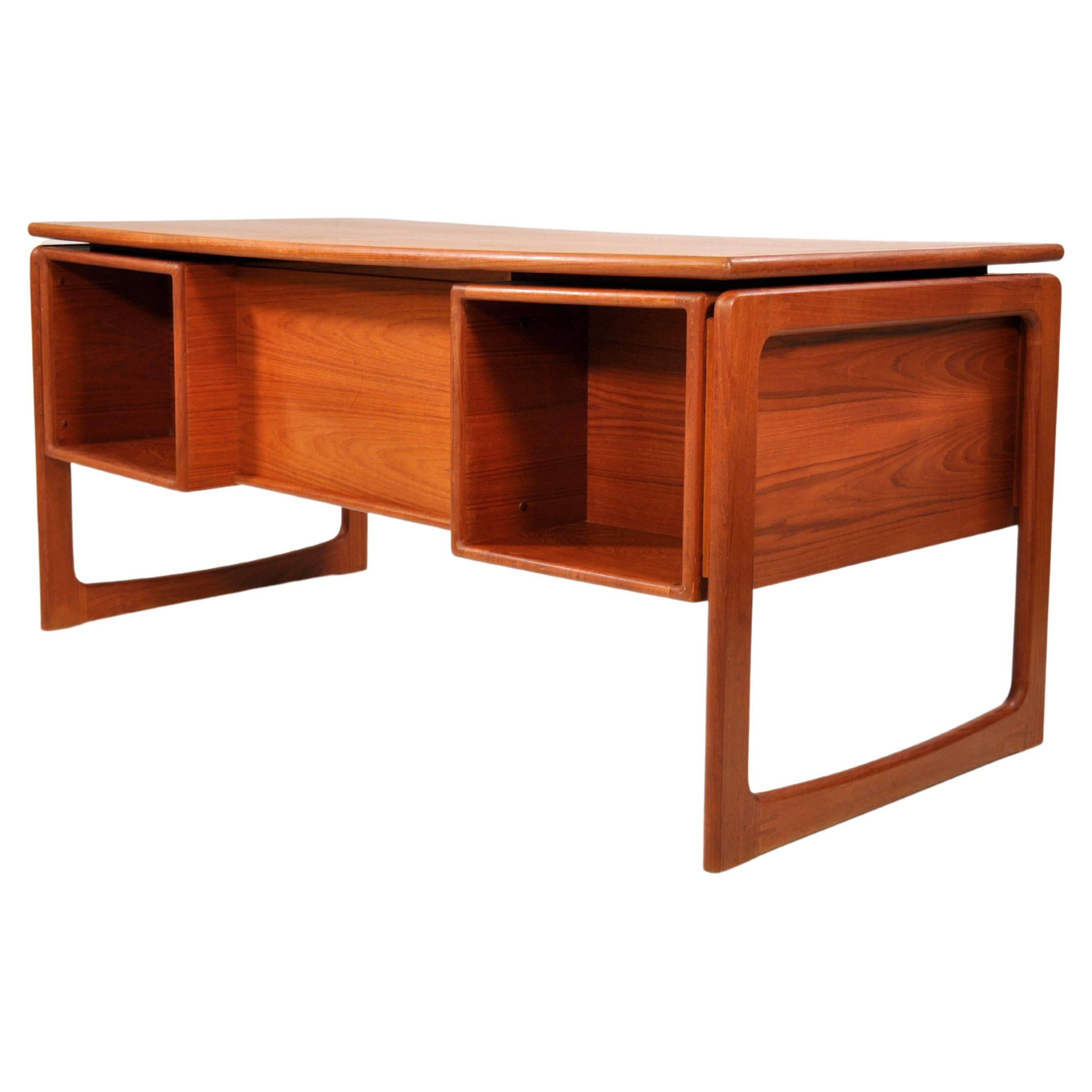 A stylish and modern teak executive desk with floating top designed and made in Denmark by Dyrlund. The Scandinavian writing table features three drawers on the left, an open filing drawer on the right, and two open bookcases in the back for