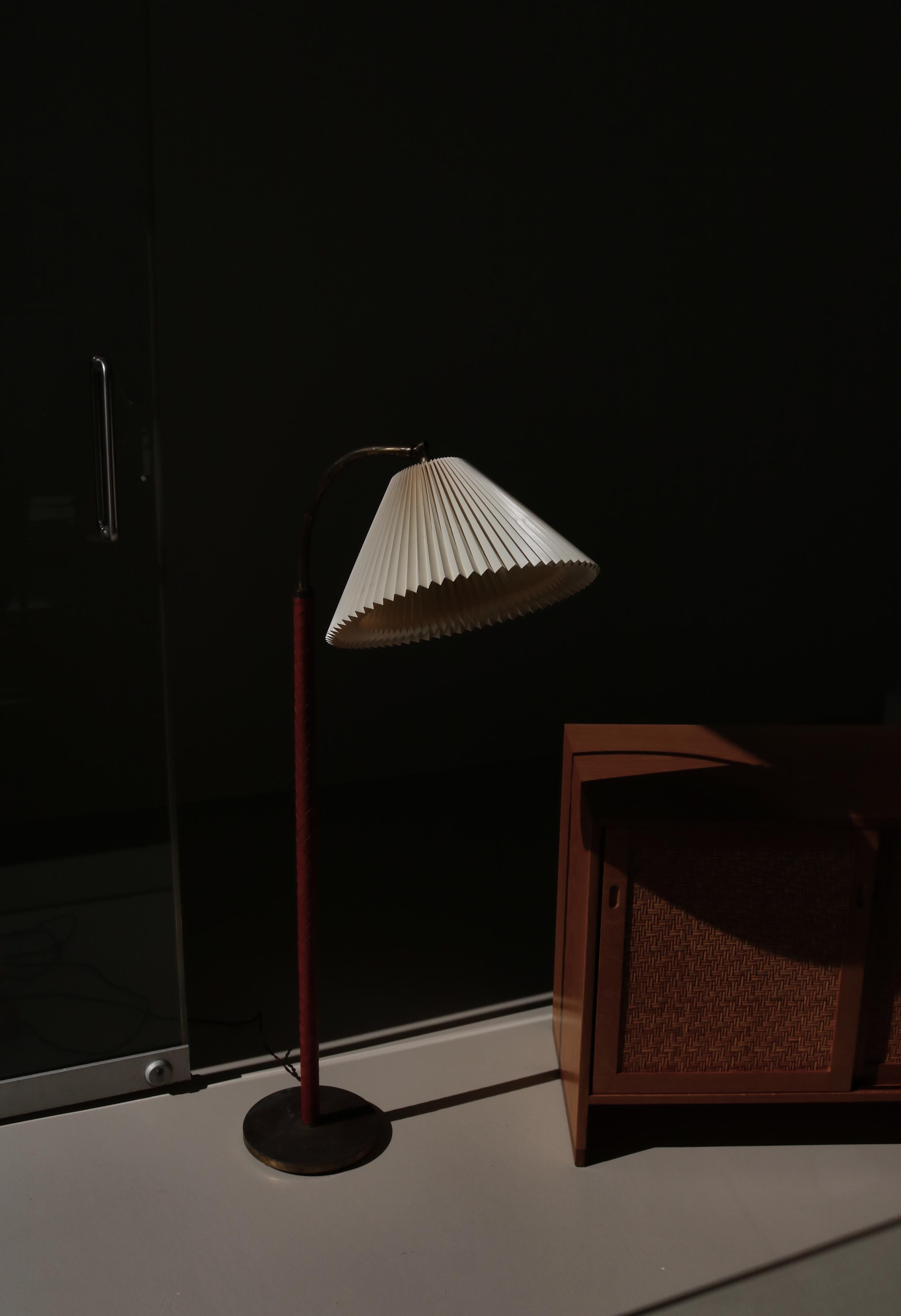Beautiful and rare Danish Modern floor lamp attributed to LYFA, Copenhagen in the 1940s. The brass stem is covered with the original patinated woven red leather and the shade is hand folded acrylic by Le Klint. It can be adjusted in height and