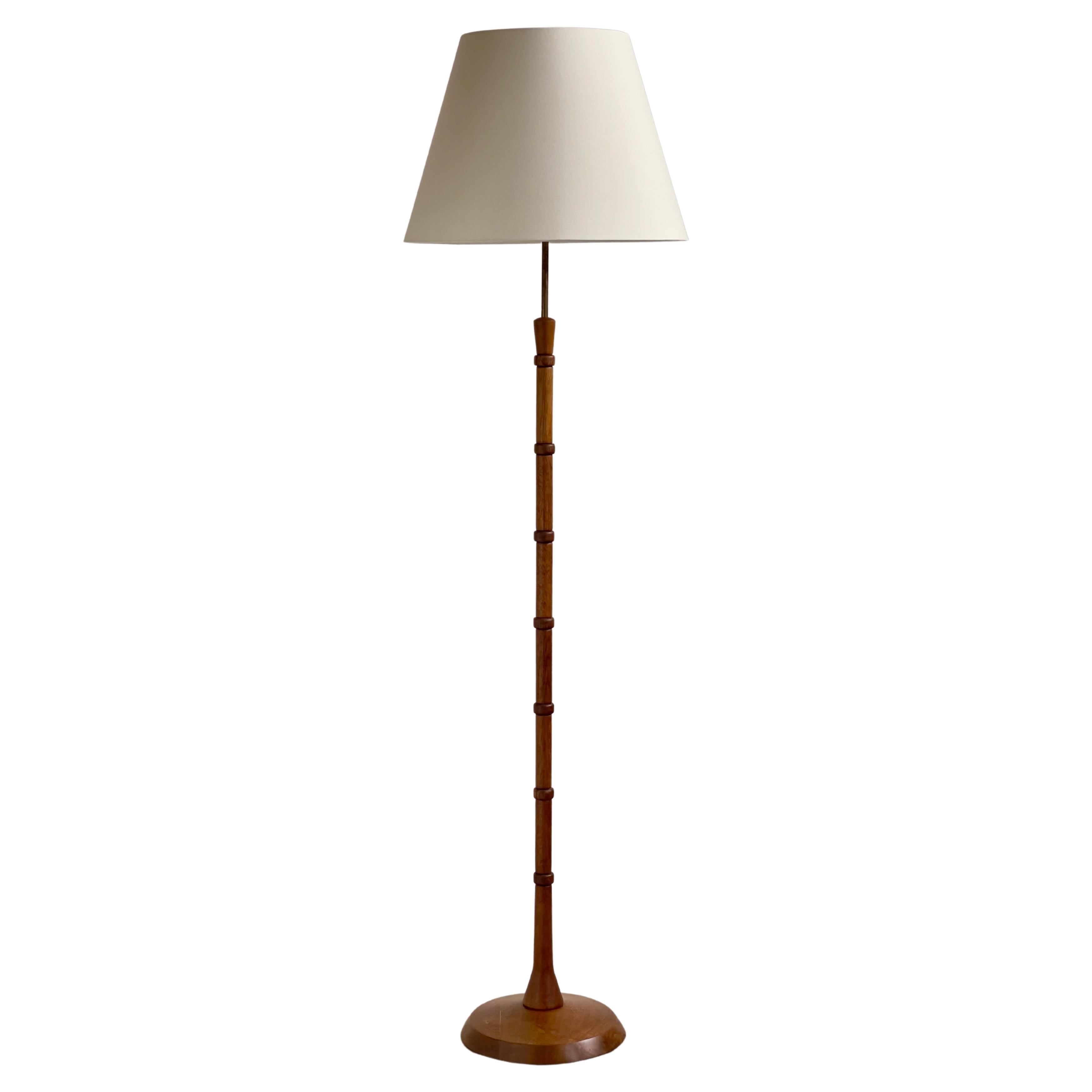 Danish modern floor lamp in patinated hand carved oak and brass, Denmark 1960s For Sale