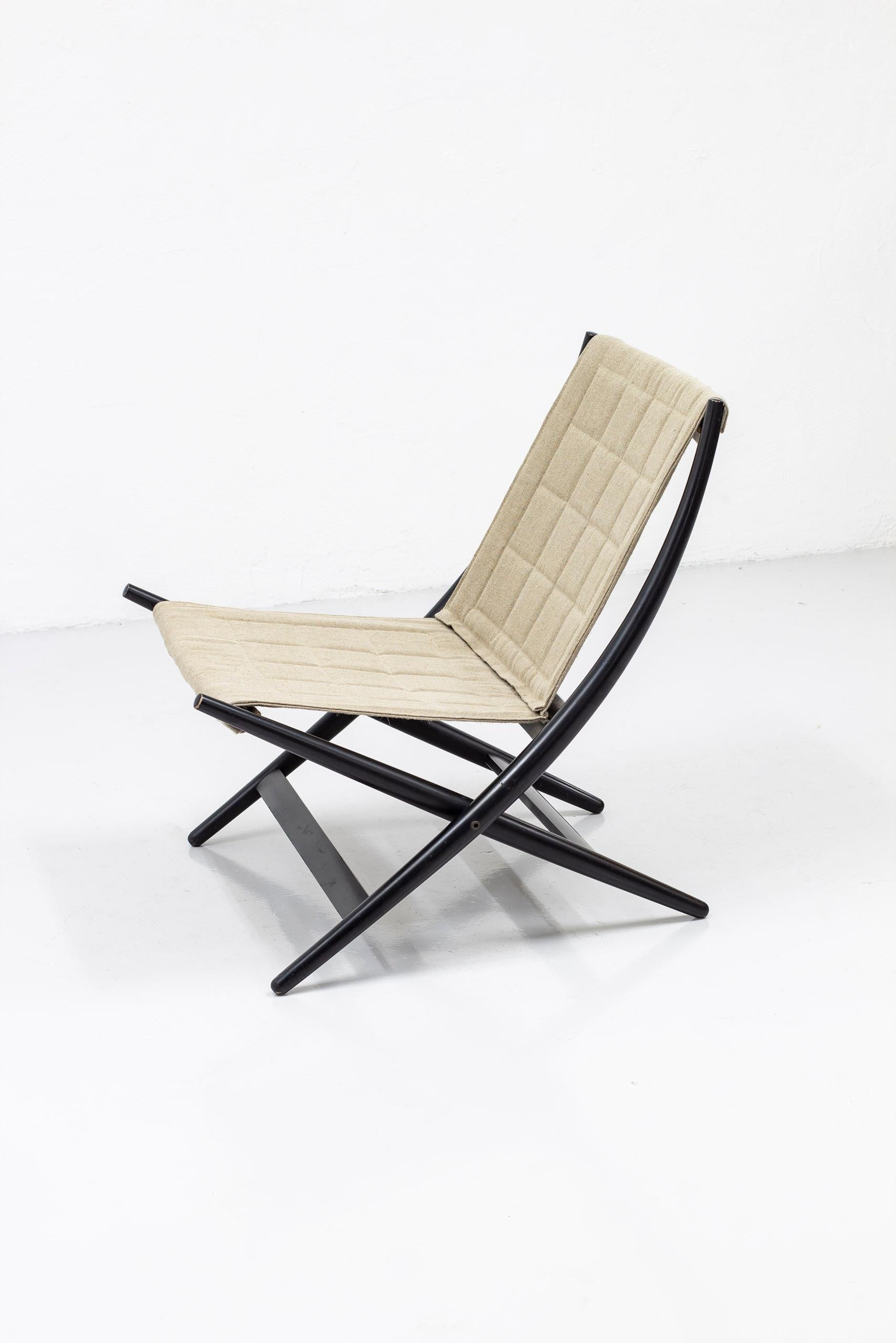 Danish folding chair designed by John Hagen in 1958. Produced by Cabinetmaker I. Christiansen in Denmark ca late 1950-1960s. Made from black lacquered beech wood with lightly padded and pattern sewn natural canvas upholstery. The upholstery is newly