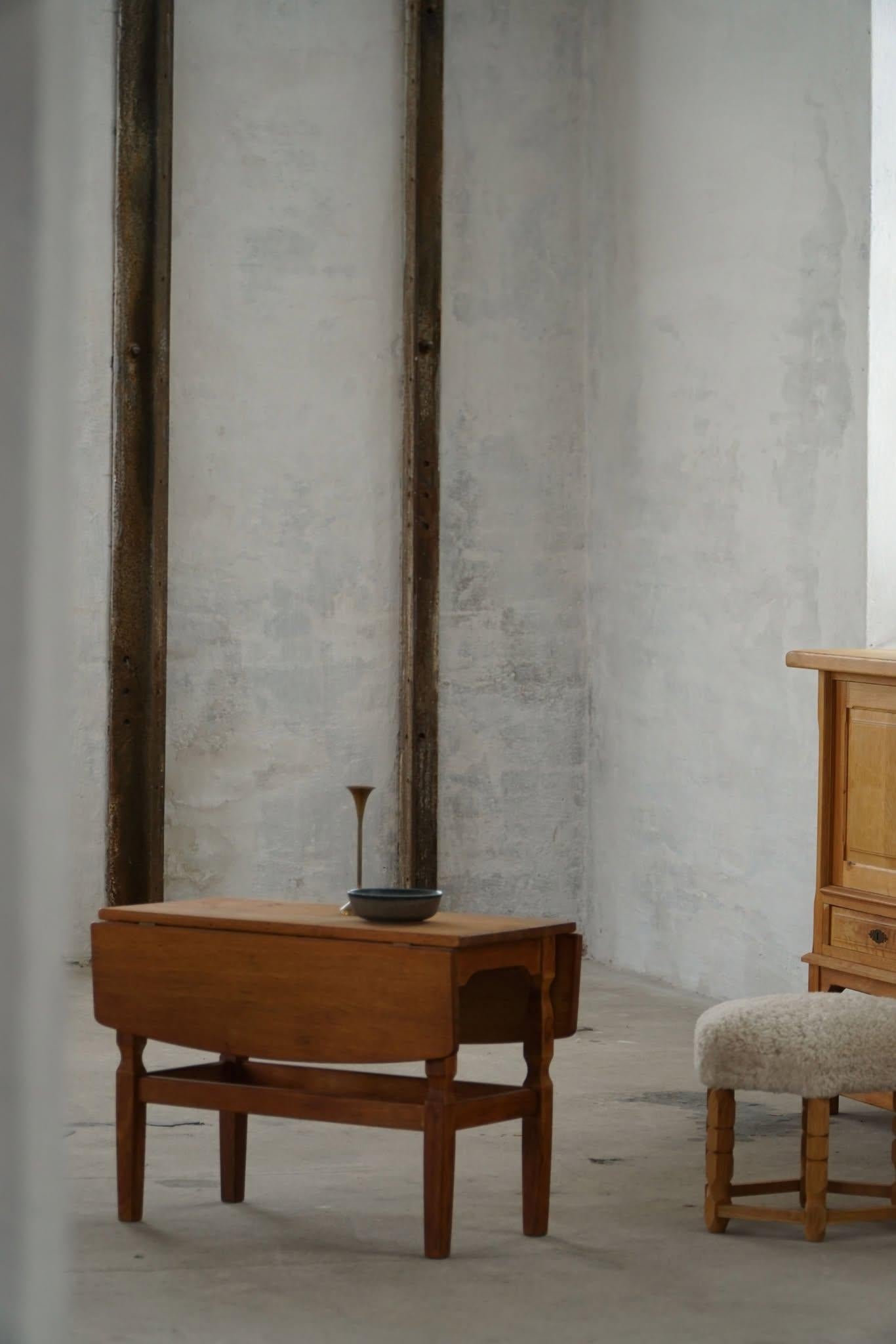 This mid-20th century folding side table exemplifies the clean, understated elegance of Danish modern design. The table includes two hinged drop leaves that extend its surface, making it adaptable as a side table. Crafted by a Danish cabinetmaker in