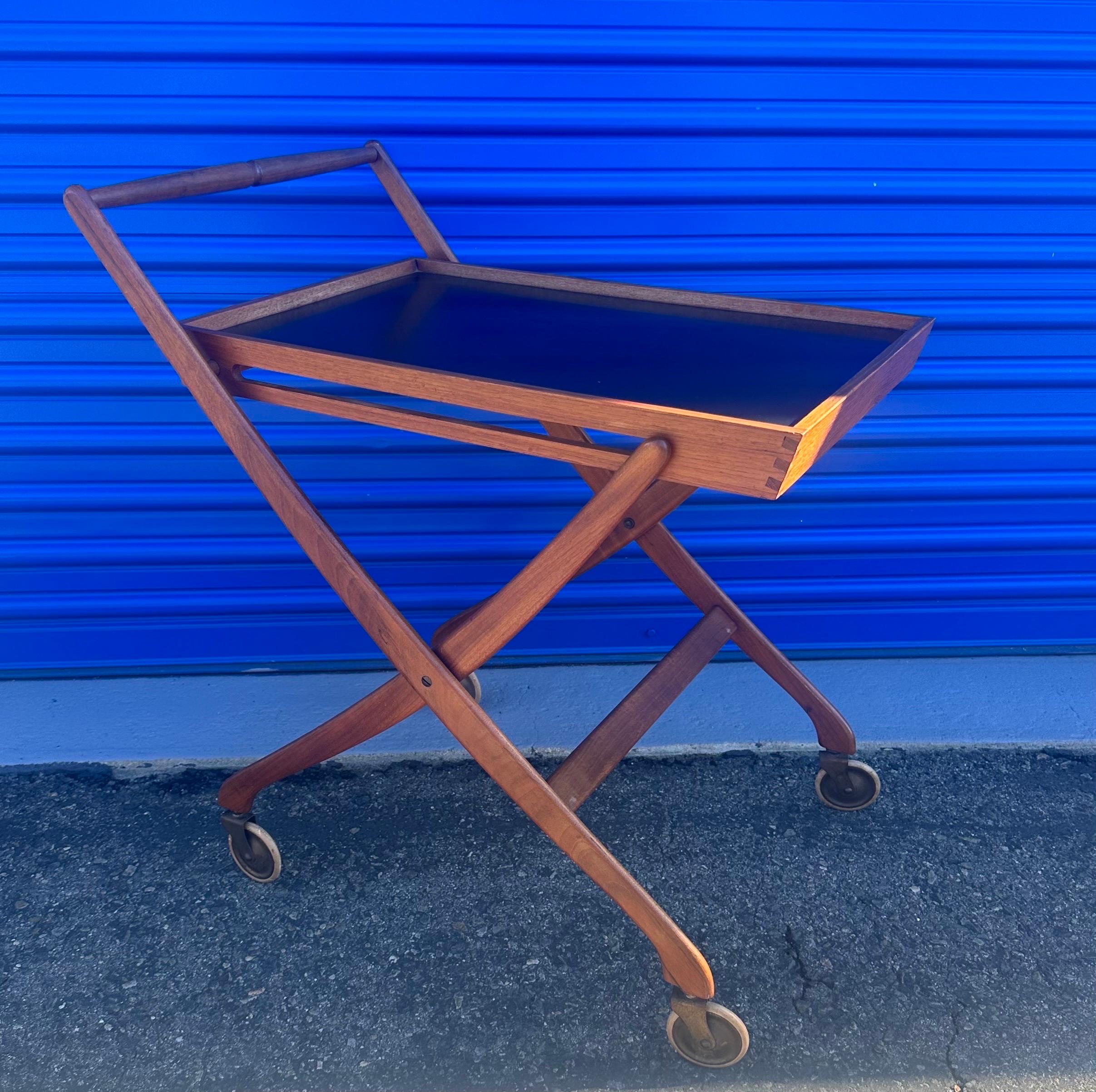 A very nice and functional Danish modern folding teak bar cart / serving trolley, circa 1960s.  Elegant and simply designed Danish bar cart on gliding wheels. Beautifully detailed wooden dovetailed joints with a black laminate serving tray top.  The