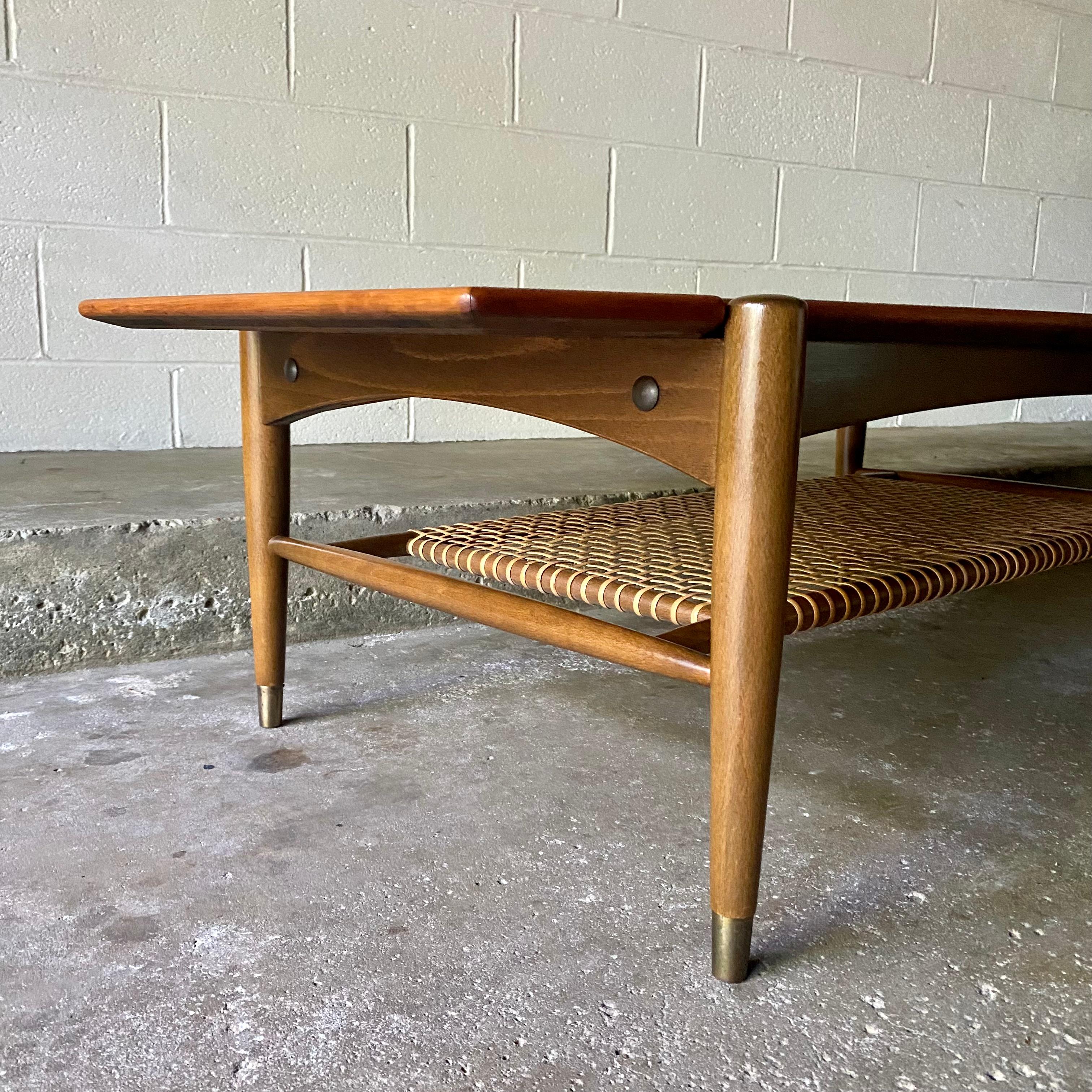 This is an excellent Danish modern coffee table designed by Folke Ohlsson for Dux of Sweden in the 1960’s. It features beautiful sculpted beech wood with a teak wood veneer top, original cane, and brass detail. It’s subtle yet impressive, large yet