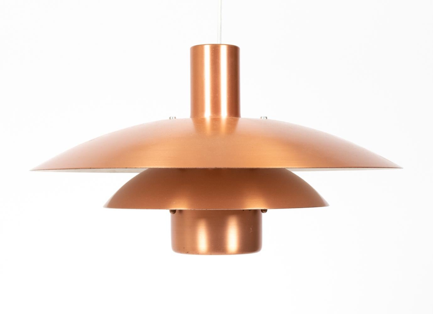 Clásica lámpara colgante danesa de mediados de siglo con forma de platillo en metal cobrizo apilado. Del fabricante danés Form Light, conserva la etiqueta original en el interior. Esta lámpara atemporal sigue el estilo de los icónicos diseños de