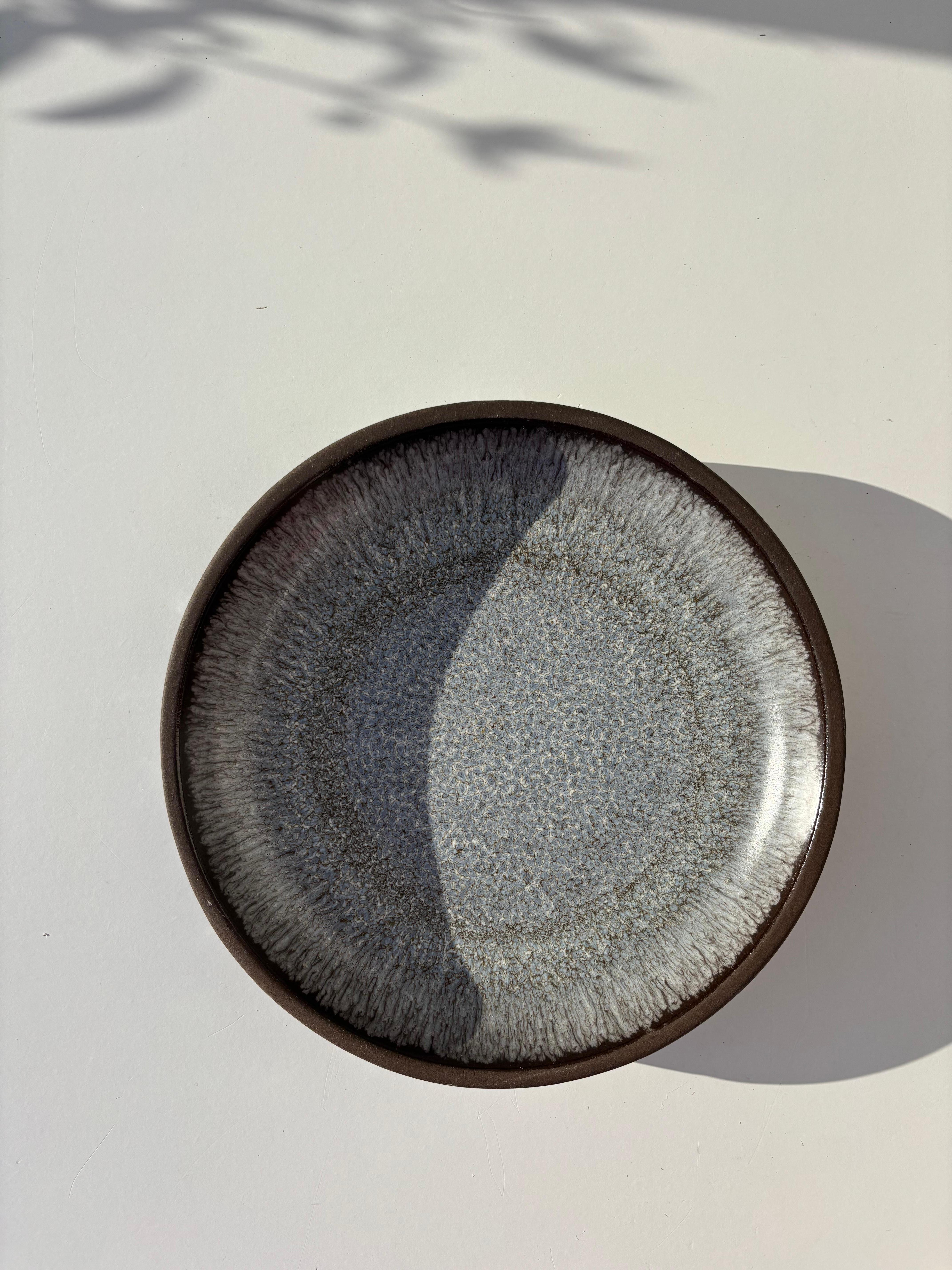 Piatto vide-poche in ceramica della metà del secolo scorso realizzato a mano dall'artista ceramista Frank Rasmussen nel suo studio Frank Keramik Denmark negli anni '60. Smalto grigio blu con macchie di caramello dorato sopra e intorno alla