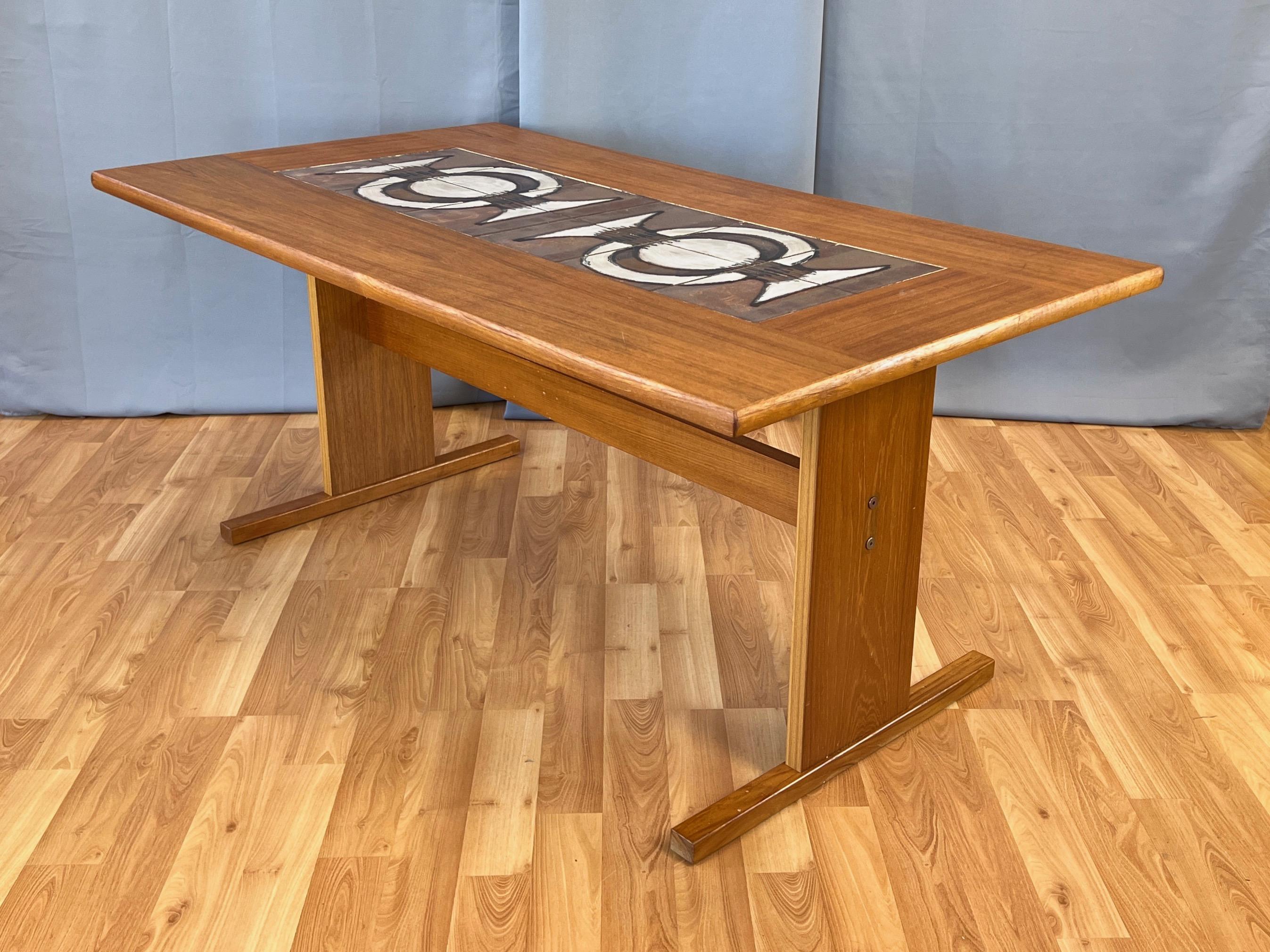 A very handsome 1970s Danish teak dining table by Gangsø Møbler with ceramic art tile top by Poul Hermann Poulsen. 

Bookmatched teak with a distinctive linear grain pattern runs the length of the rounded-edge top, with perpendicularly-aligned
