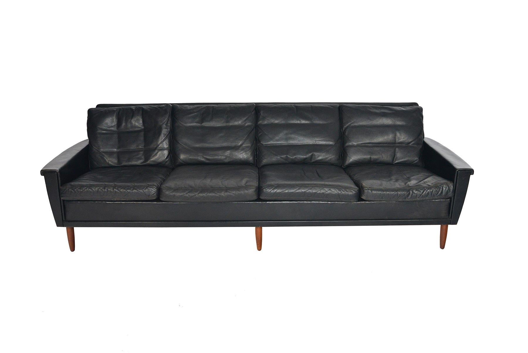This long Danish modern four seat sofa was manufactured by Georg Thams in the 1960s. The slender upholstered frame holds eight leather cushions. Sofa stands on five teak spindle legs. In excellent original condition. 

