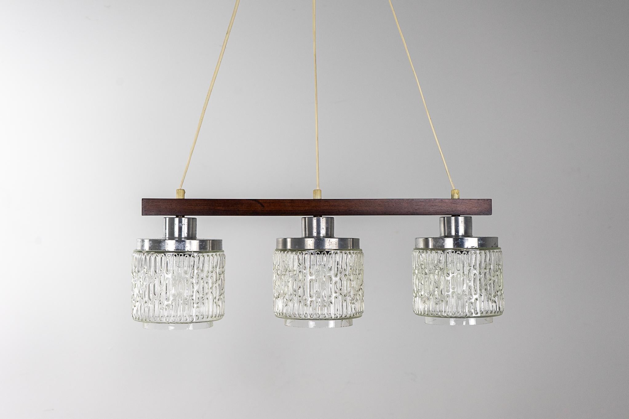 Rosewood and glass Danish modern pendant light, circa 1960's. Triple light chandelier with original heavily textured glass shades and silver metal caps. Light the space you love!

Please inquire for international and remote shipping rates.