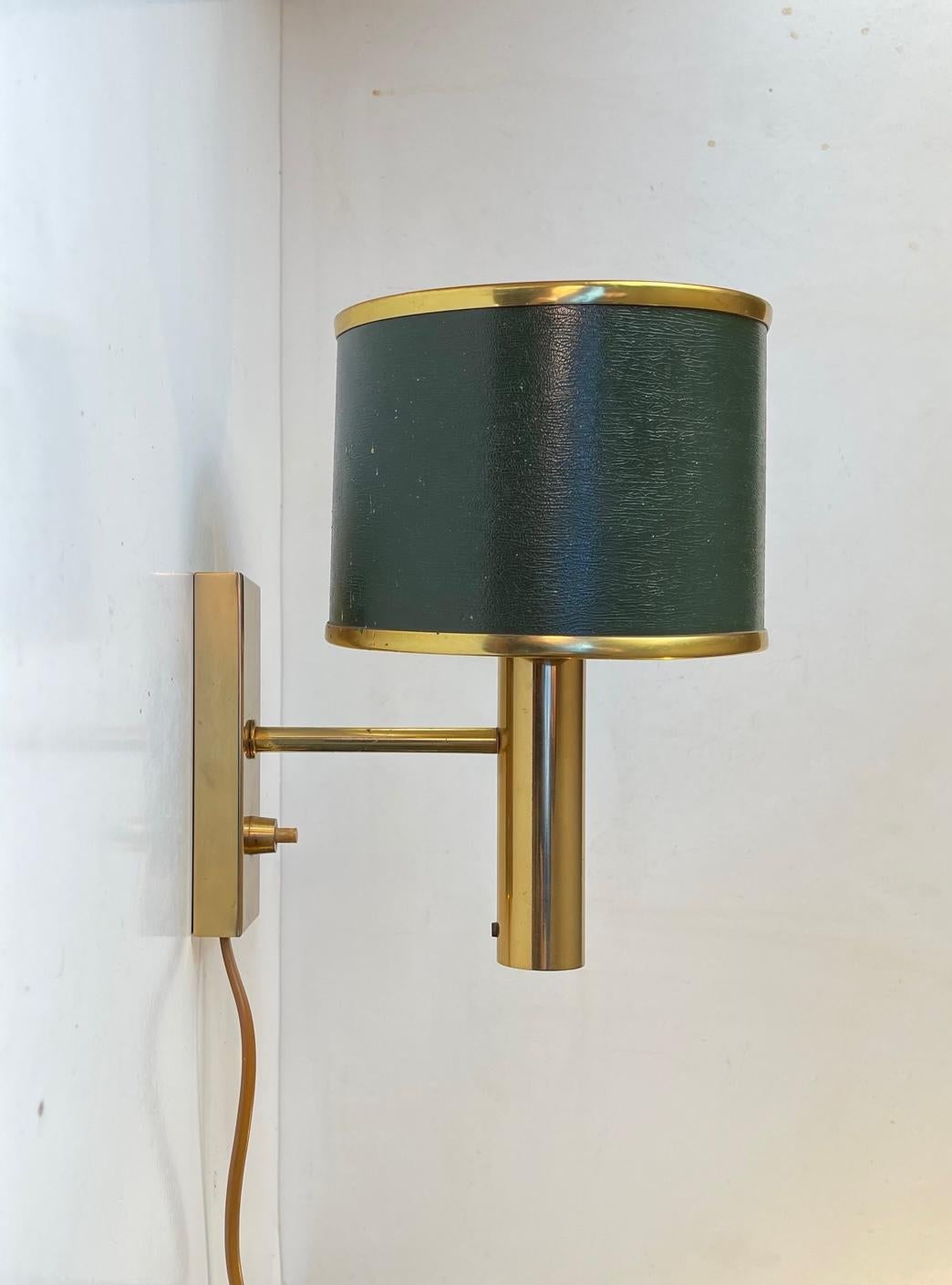 A classic Scandinavian Modern Wall light called Jason and designed by Jo Hammerborg and manufactured by Fog & Mørup in Denmark during the 1970s. It features hardware in solid polished brass and its original green shade with brass accents.