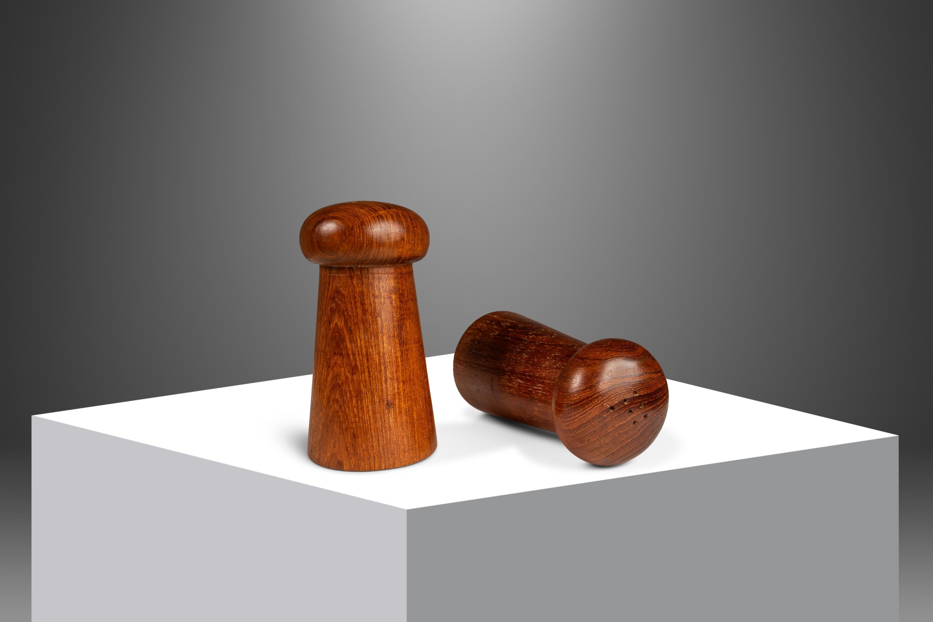  Te presentamos un encantador juego de salero y pimentero de fabricación danesa y torneado a mano. Tallado en teca birmana maciza con excepcionales vetas de madera por todas partes, este moderno conjunto orgánico es tan estético como práctico.