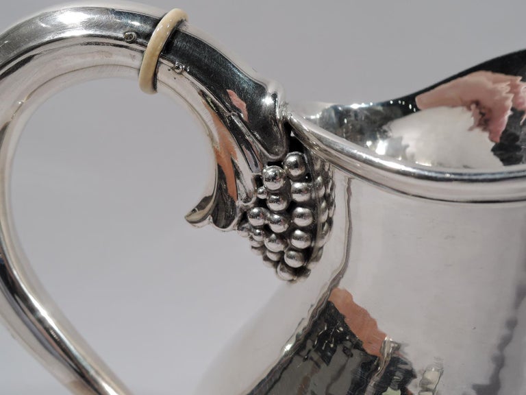 Mid-Century Modern sterling silver water pitcher. Made by Svend Toxværd in Copenhagen. Baluster body with helmet mouth and grape-bunch mounted scroll handle. Alternating grape bunches and palmettes applied to base. Body has all-over hand hammering.