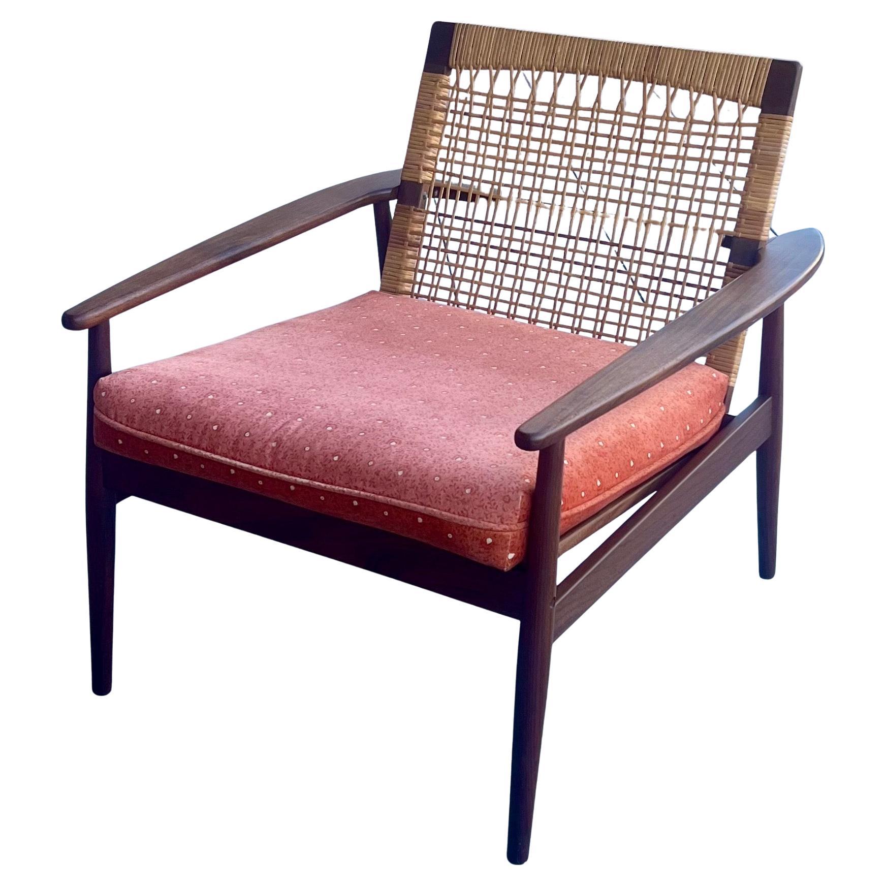 Danish modern lounge chair designed by Hans Olsen for Juul Kristensen in Denmark circa 1950s. This iconic chair by Hans Olsen is constructed from solid Afromosia teak wood that is found only in Africa,  Danish woven caned backrest and steel coil