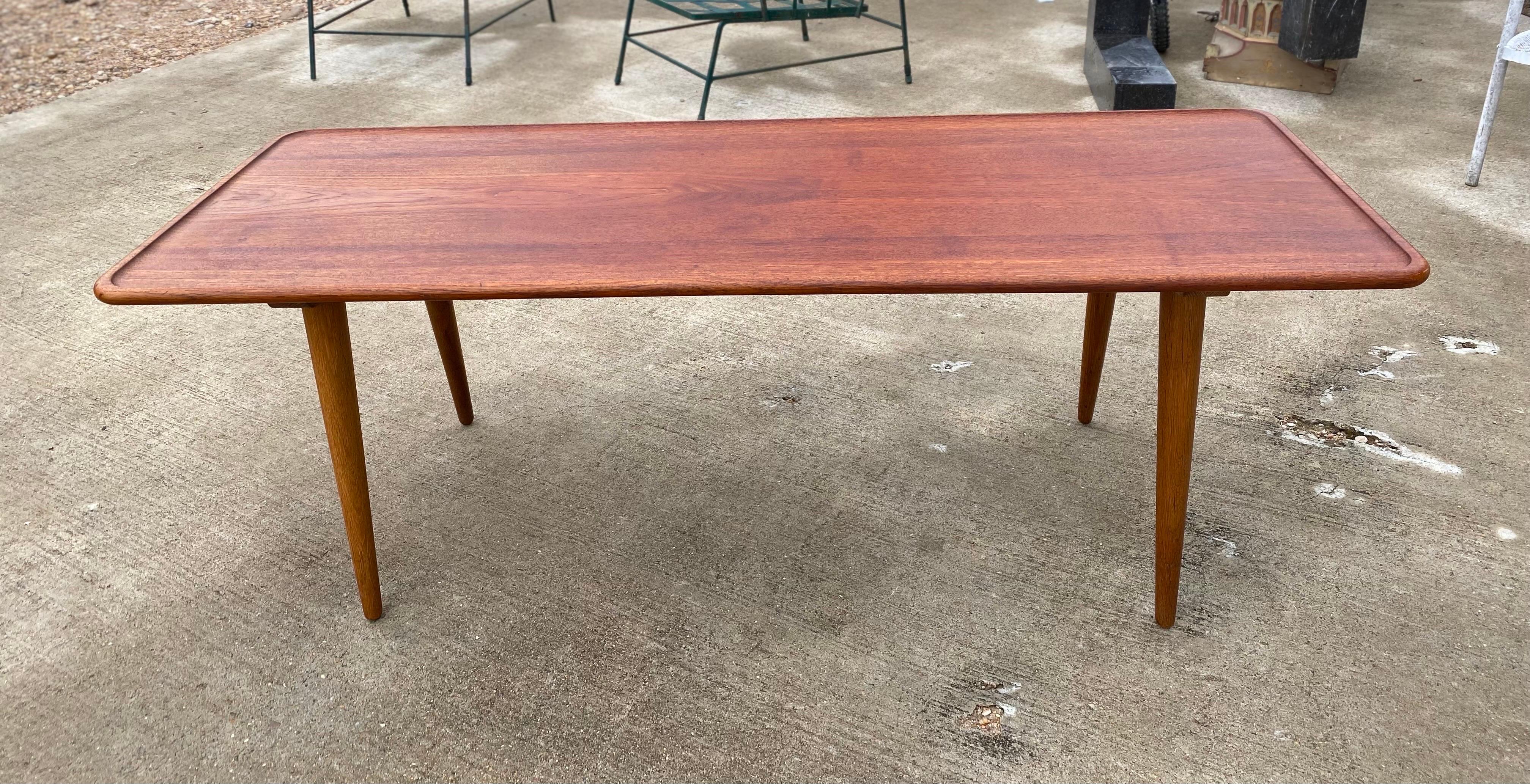 Scandinavian danish modern coffee table designed by Hans Wegner features a teak sculpted lip and top with tapered legs made of oak. This coffee table is in good condition and is stamped on the underside of the table. 

Table measurements: 

Hans