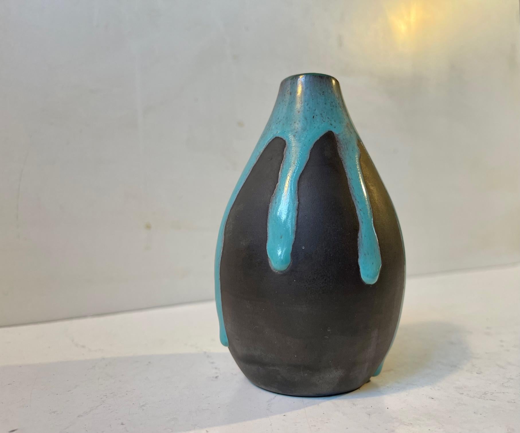 Ceramic vase decorated with petrol blue greenish drip-glaze. Designed by the danish ceramist Helge Østerberg and manufactured at his own studio during the 1960s. Its signed Ø. Measurements: Height: 12 cm, Diameter: 8 cm.