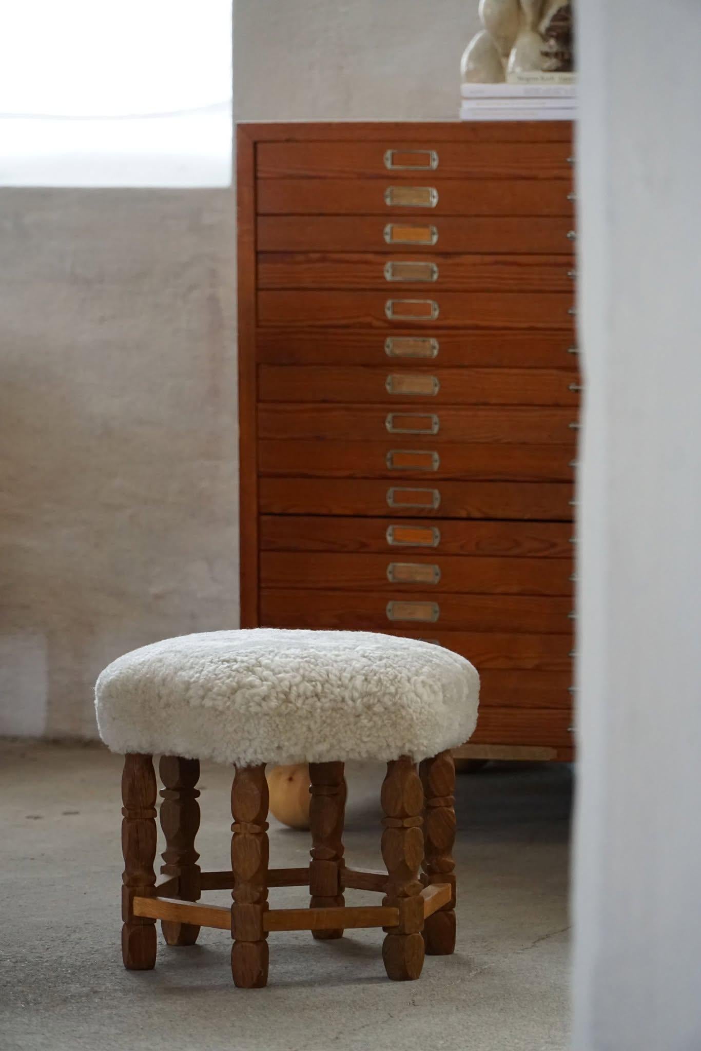 A Danish modern stool in oak, featuring distinctive curly legs and a hexagonal seat newly upholstered in high-quality light cream lambswool. Crafted by a Danish cabinetmaker in the 1950s, this fine piece presents a refined yet inviting aesthetic.