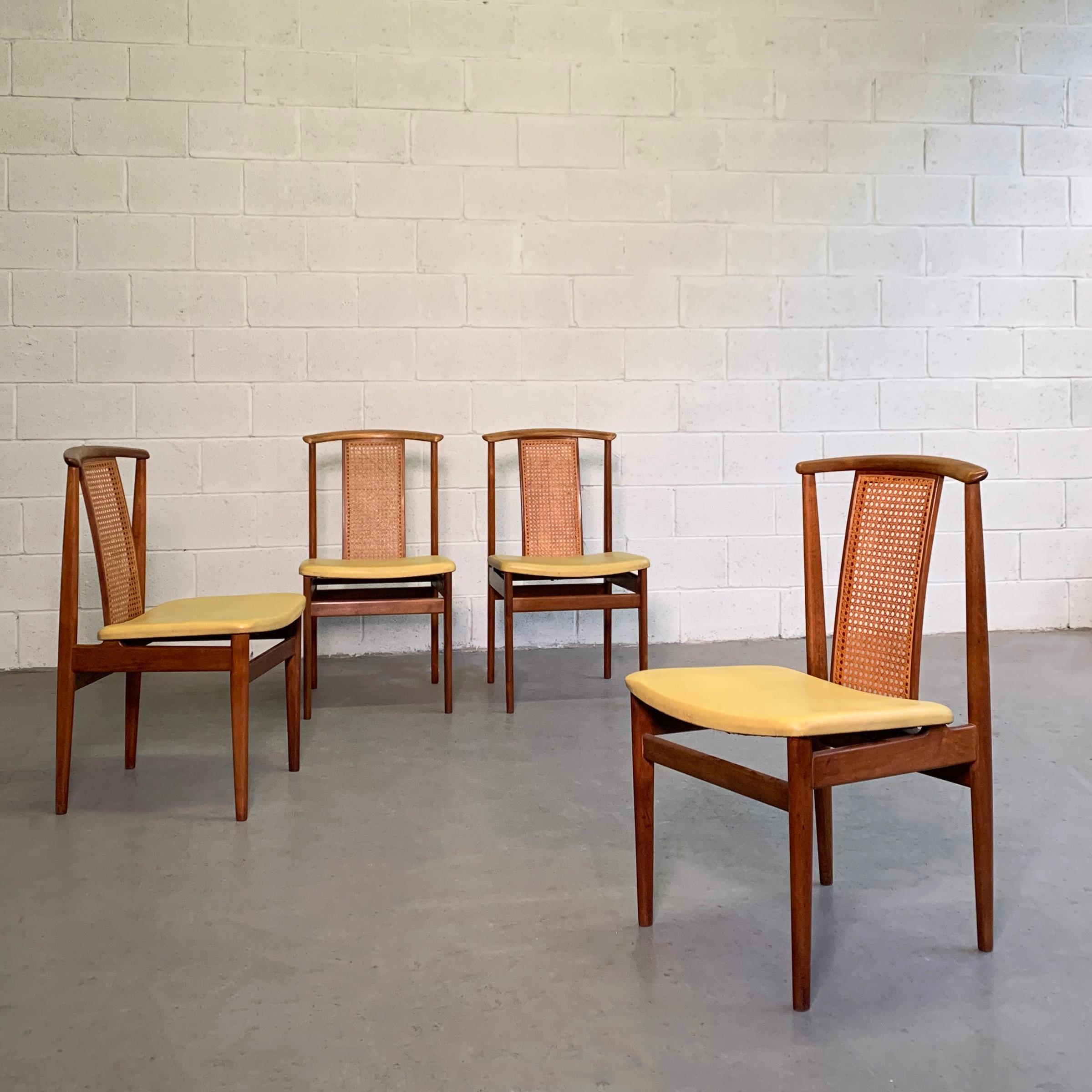Set of 4 Danish modern, teak dining chairs feature high sculpted backs with cane detail and vinyl upholstered seats.
