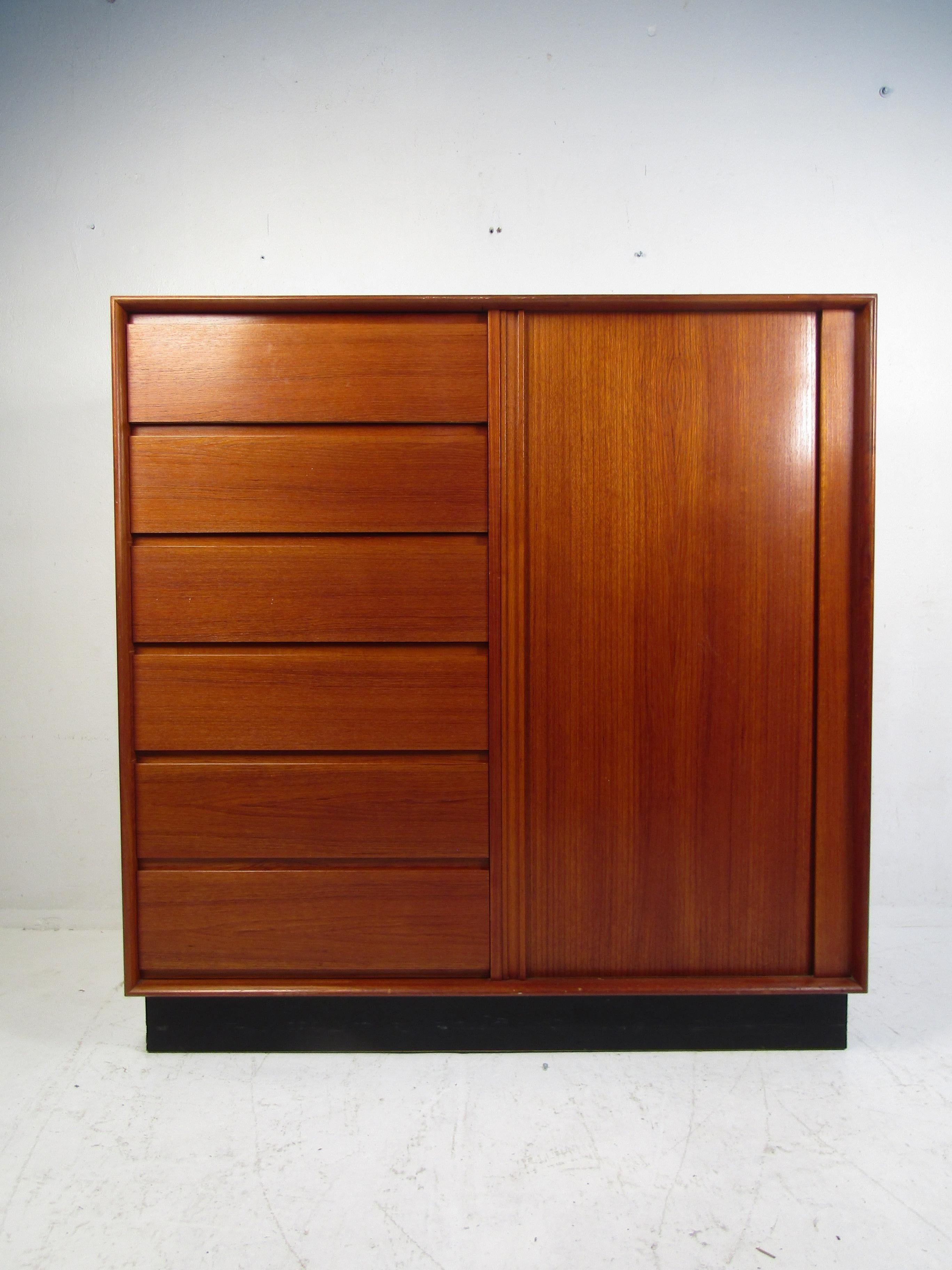 Stylish Danish midcentury high dresser. Teak wood exterior, with a black skirt base. Ample storage space between the dresser drawers on the left, and the sliding drawers on the right which are concealed by a well-made tambour door. A great piece