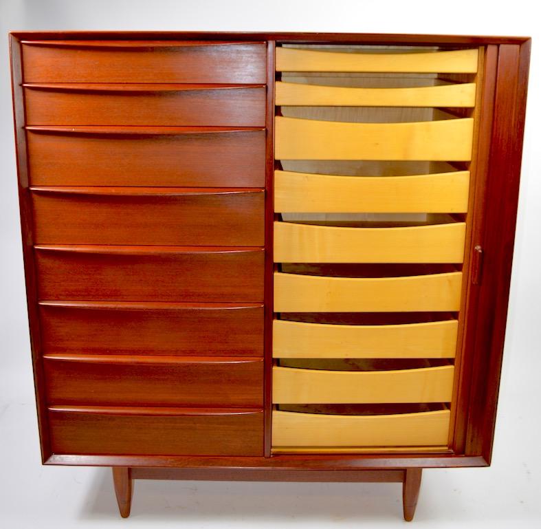 Nice teak highboy, Chifferobe by Falster, in very good original condition, showing only light cosmetic wear, normal and consistent with age. One side has a tambour roll door which opens to reveal interior drawers, the other side has deeper drawers