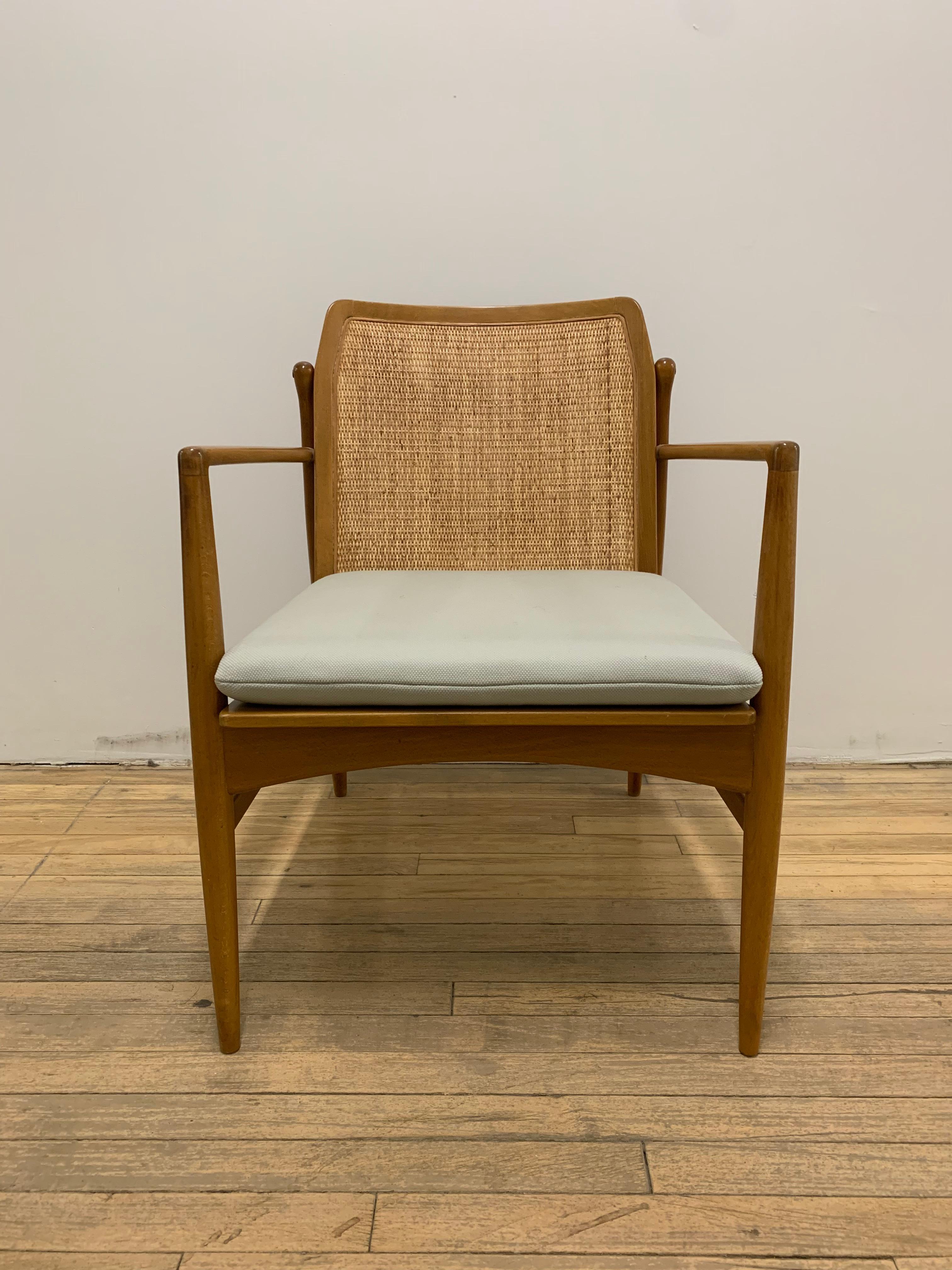 These Kofod-Larsen beech lounge chairs feature a cane back, wool seat, and understated curved details throughout the frame. First photo shows chairs before the cane was cleaned, additional photos are post cleaning. This listing includes the set of