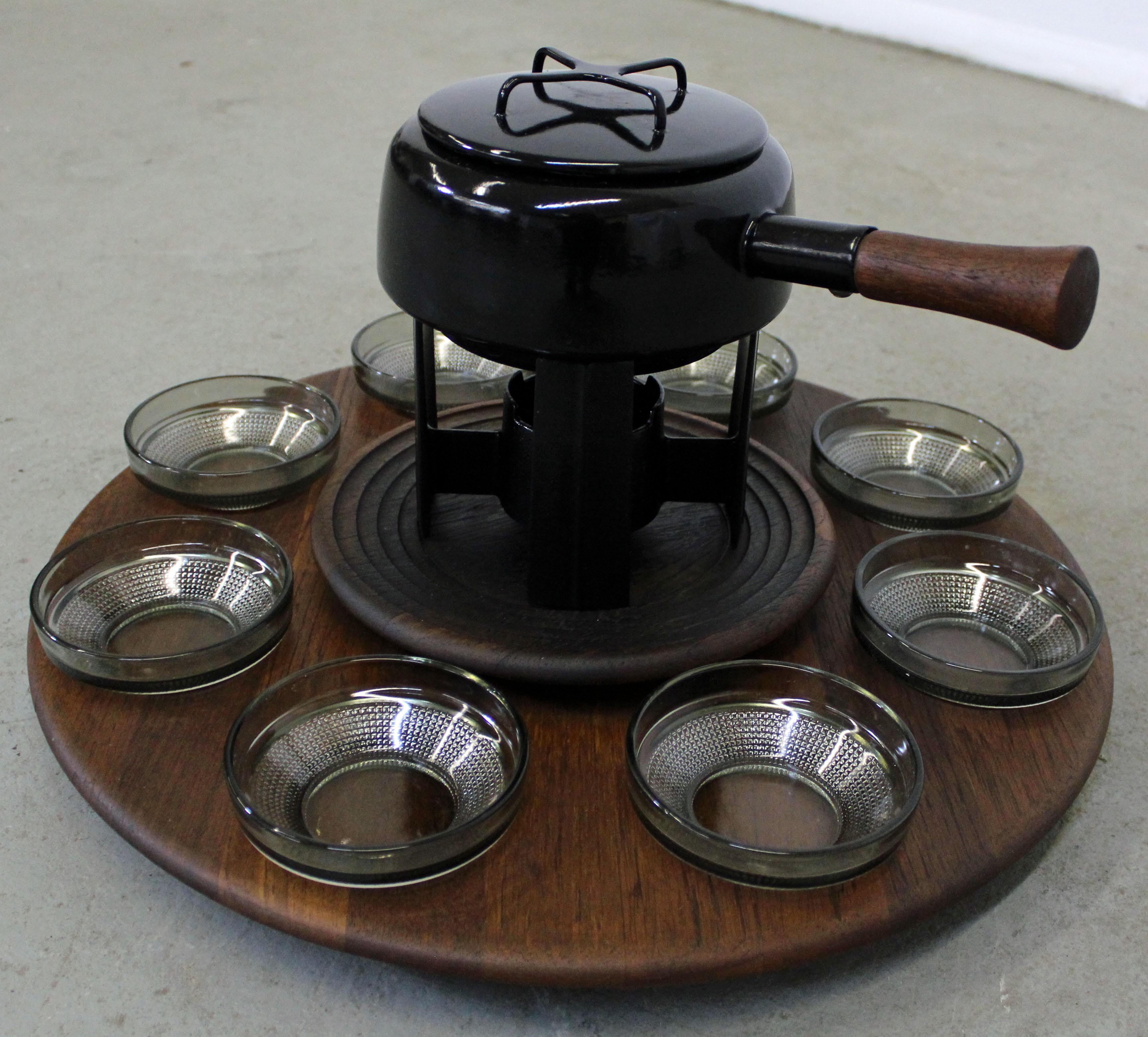 Offered is a Danish modern teak fondue set, designed by Jens Quistgaard for Dismed circa 1964. Includes a teak server with a lazy susan, eight glass bowls, enameled fondue pot, and cast iron warmer. It is in very good condition for its age, shows