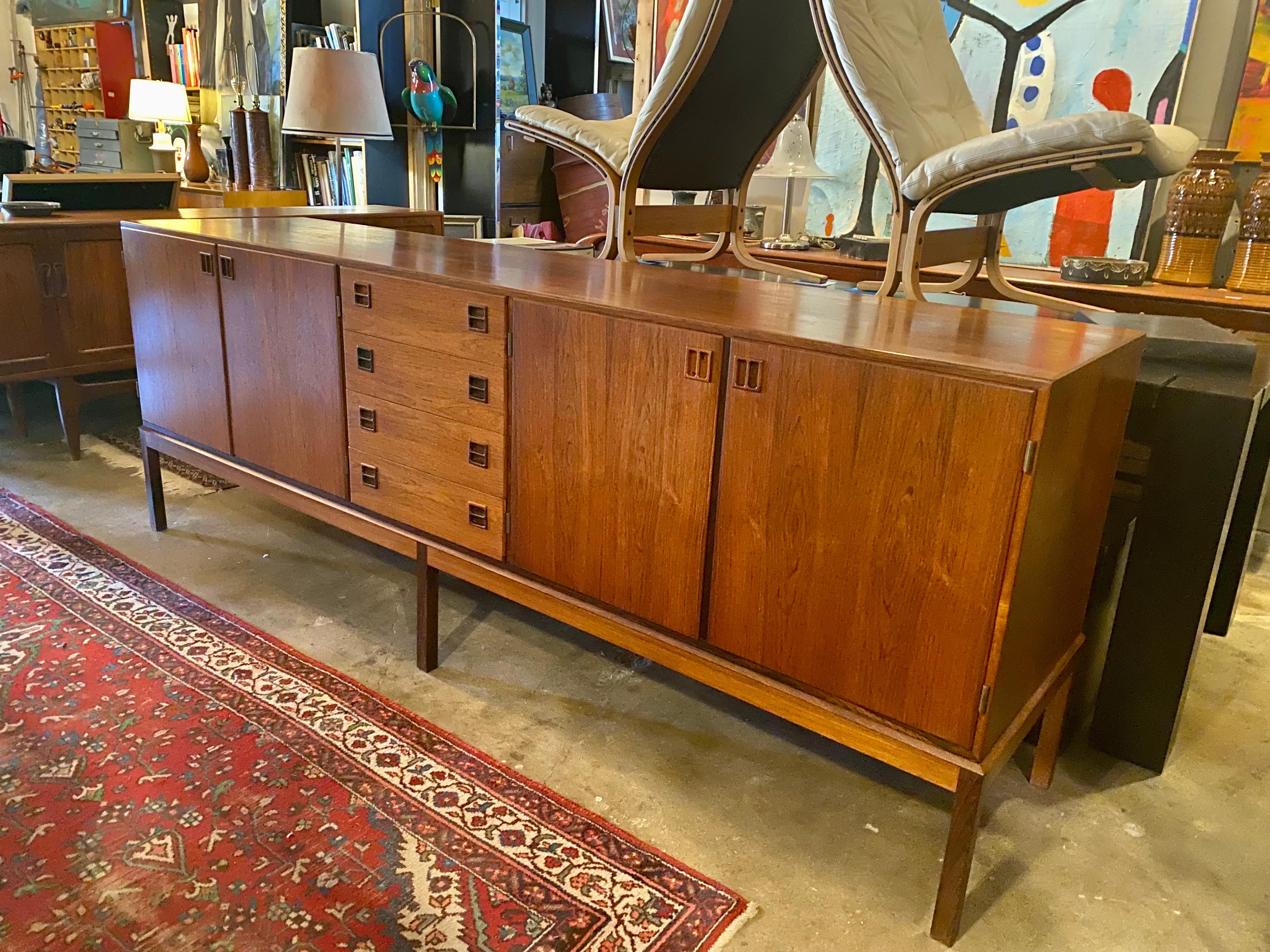 Danish modern sideboard by Johannes Andersen for Bernhard Pedersen & Son made of rosewood features plenty of storage space and beautifully sculpted handles. The left side of the credenza opens up to adjustable shelving and four trays lined with