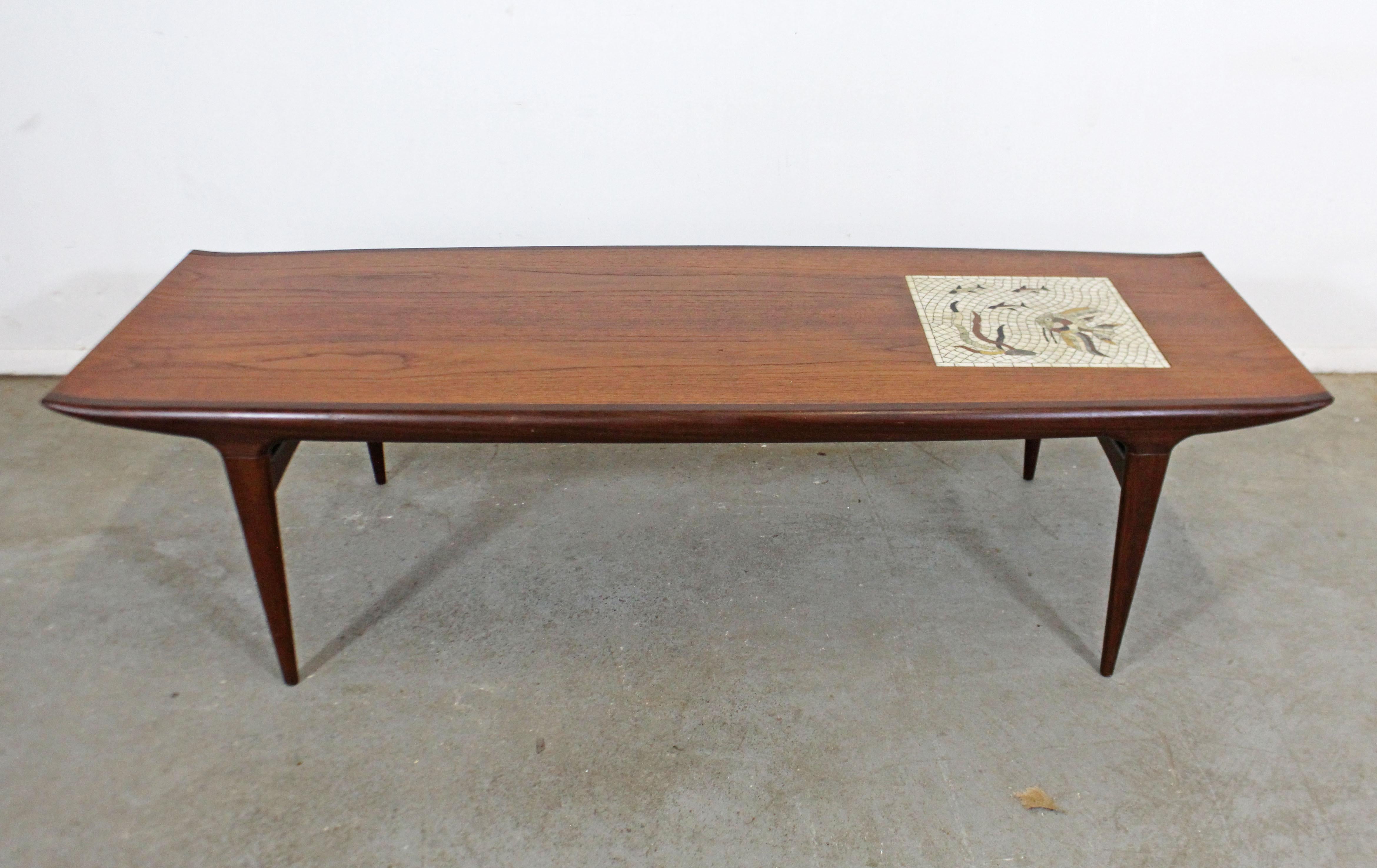 What a find! Offered is a vintage Danish modern teak coffee table with sculpted legs and top. Features a unique mosaic tile design on the tabletop with an underwater/Fish Design. It is in good condition with some age wear (see photos). It is signed