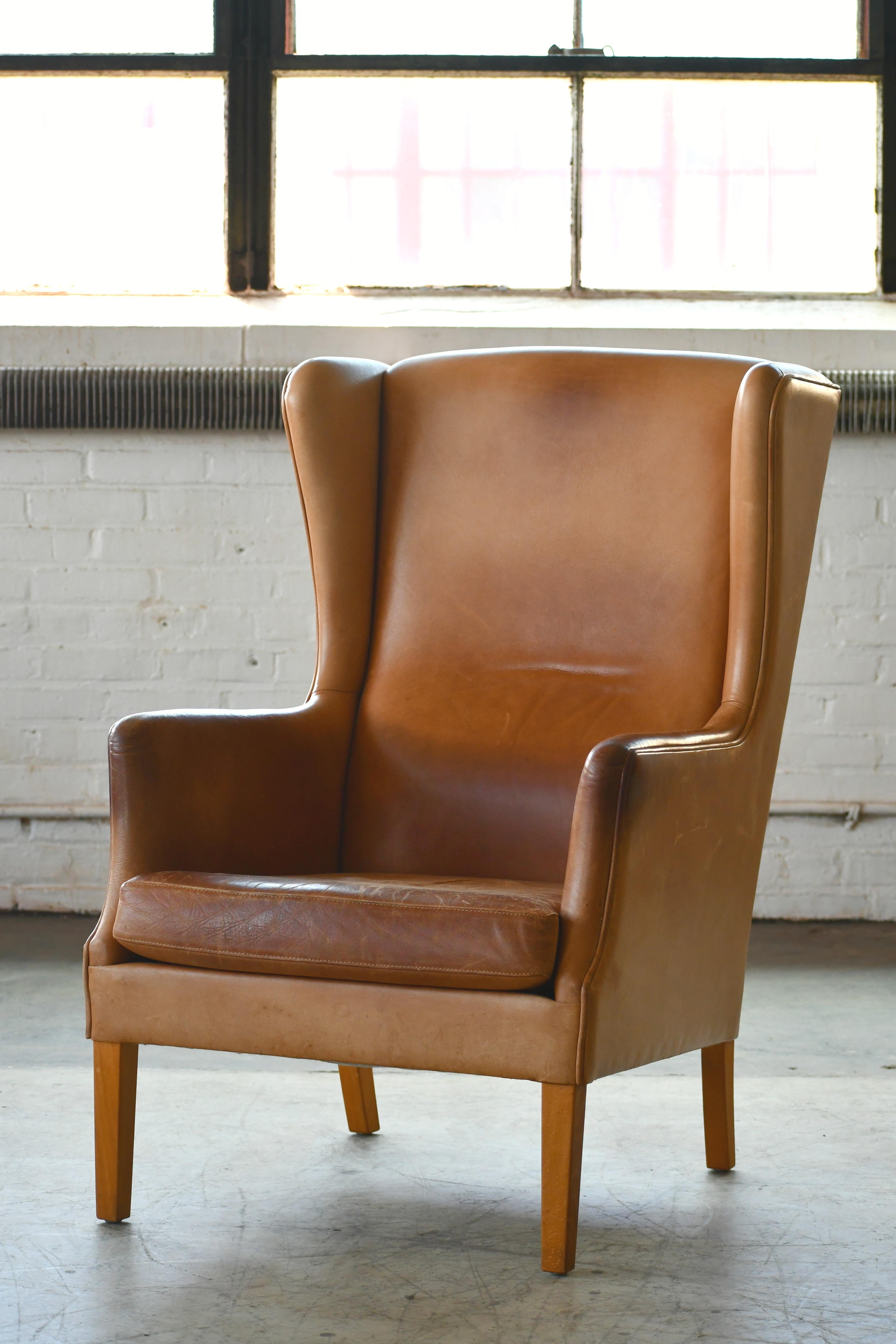 Stylish Danish circa late 1960s wingback chair in the style of Kaare Klint's famous wing back chair from 1941. The chair in unmarked and we are not sure of the maker. Nice clean lines and Classic elegance yet sturdy and comfortable raised on legs of