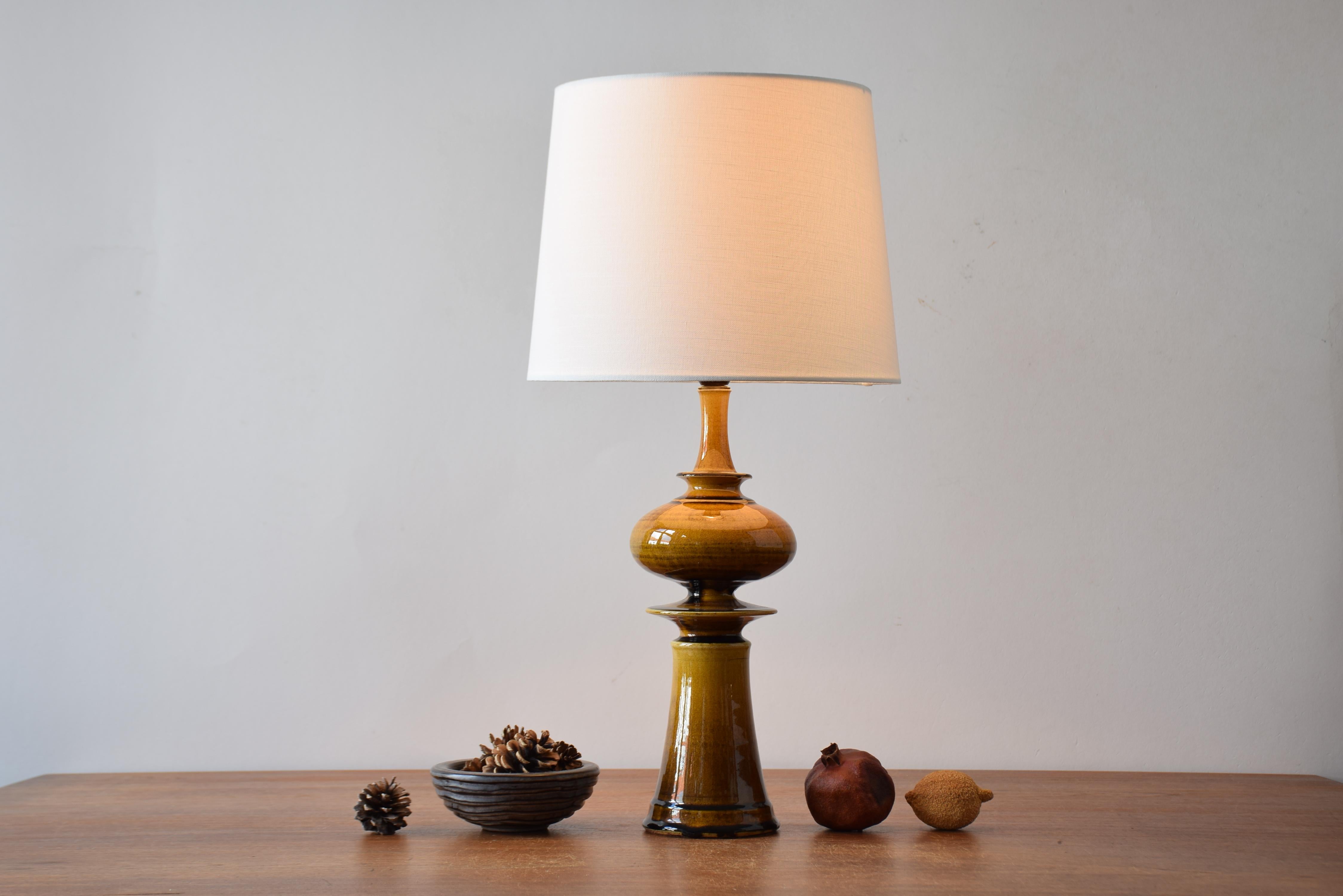 Sculptural Mid-century Danish table lamp from the ceramic studio Kähler (HAK). The lamp was designed by Poul Erik Eliasen and manufactured ca. 1960s or early 1970s.

The lamp is made of stoneware and has a glossy amber yellow glaze. The ceramic part