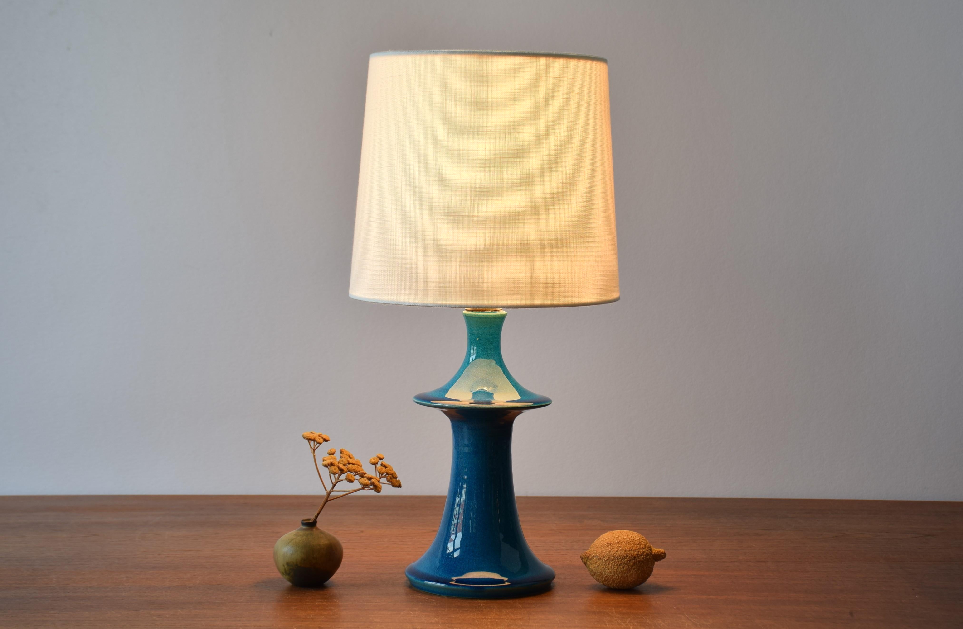 Small mid-century Danish table lamp from the ceramic workshop Kähler (HAK).
The lamp is made from stoneware and has a shiny turquoise blue glaze.
The design is most likely by Poul Erik Eliasen. Made circa 1960s.

On bottom the lamp base is