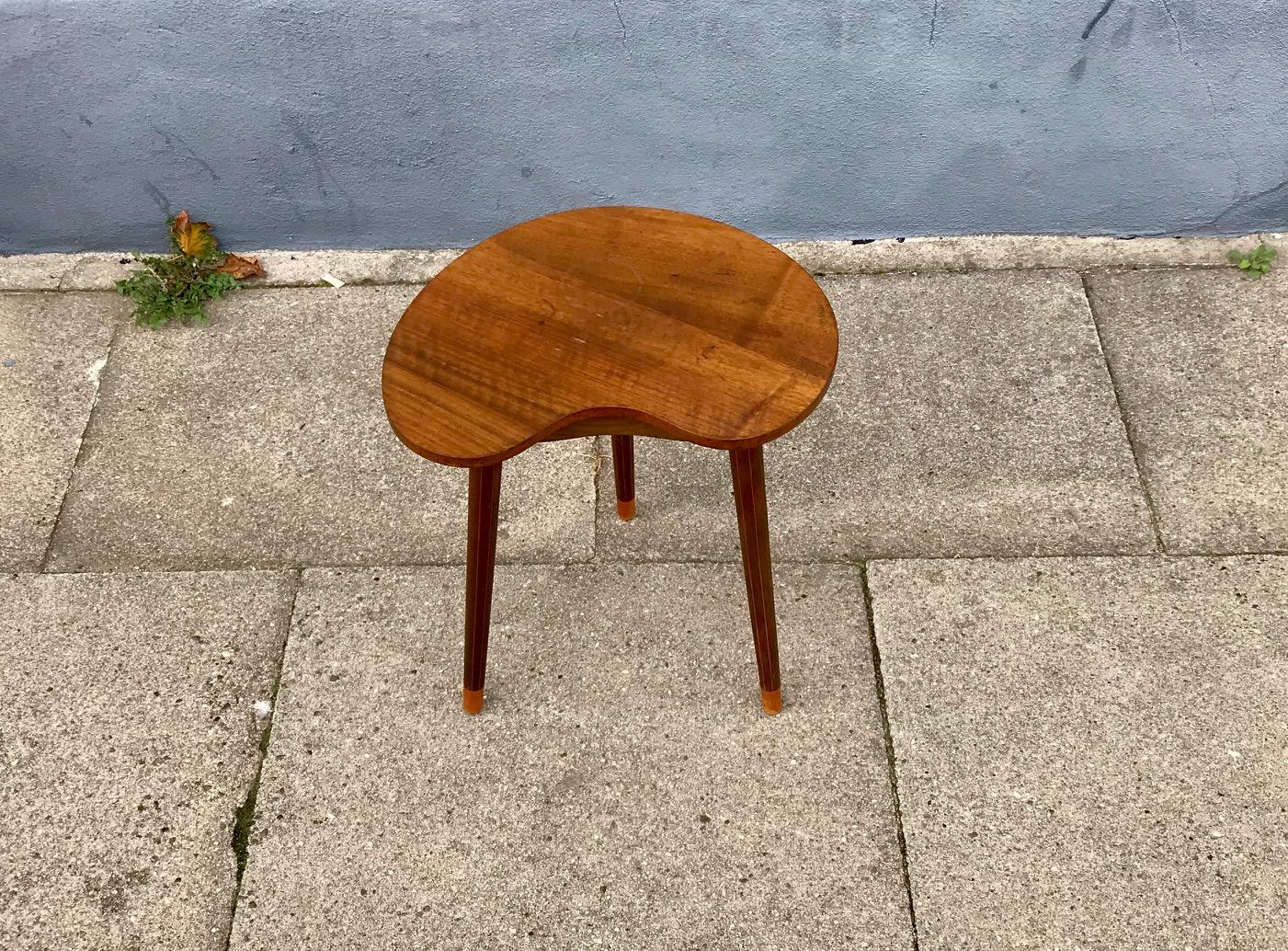 This early three-legged kidney or bean shaped side table was designed by Edmund Jørgensen in Nakskov, Denmark, during the 1950s. It features cherry-inlaid pinstripes to the 3 legs. It will be shipped as a package with the legs unscrewed from the top.
