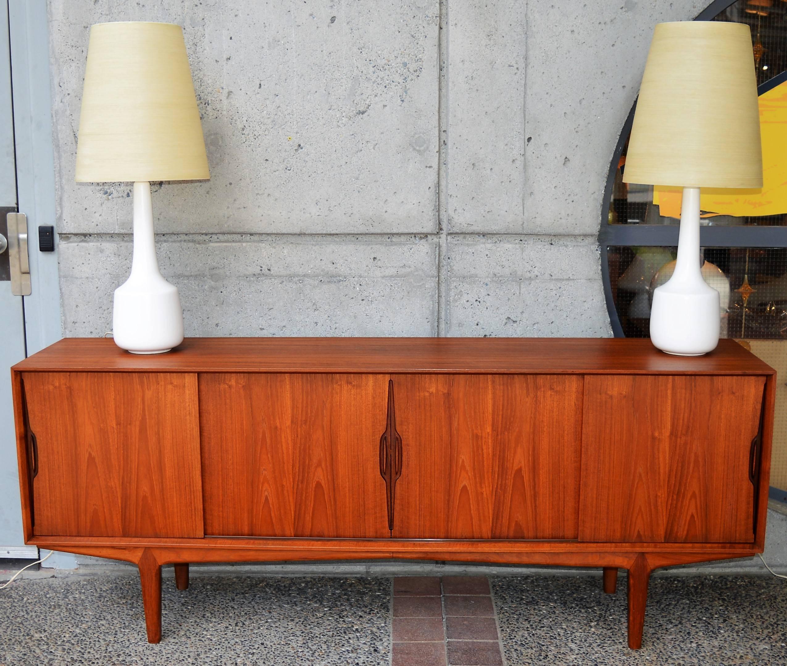 This stellar Danish teak buffet / credenza was designed by Knud Nielsen and has his iconic sculptural door pulls with a darker inside to really make them pop. Featuring clean, modern lines with crisp edges and a mitered front edge molding detail, as
