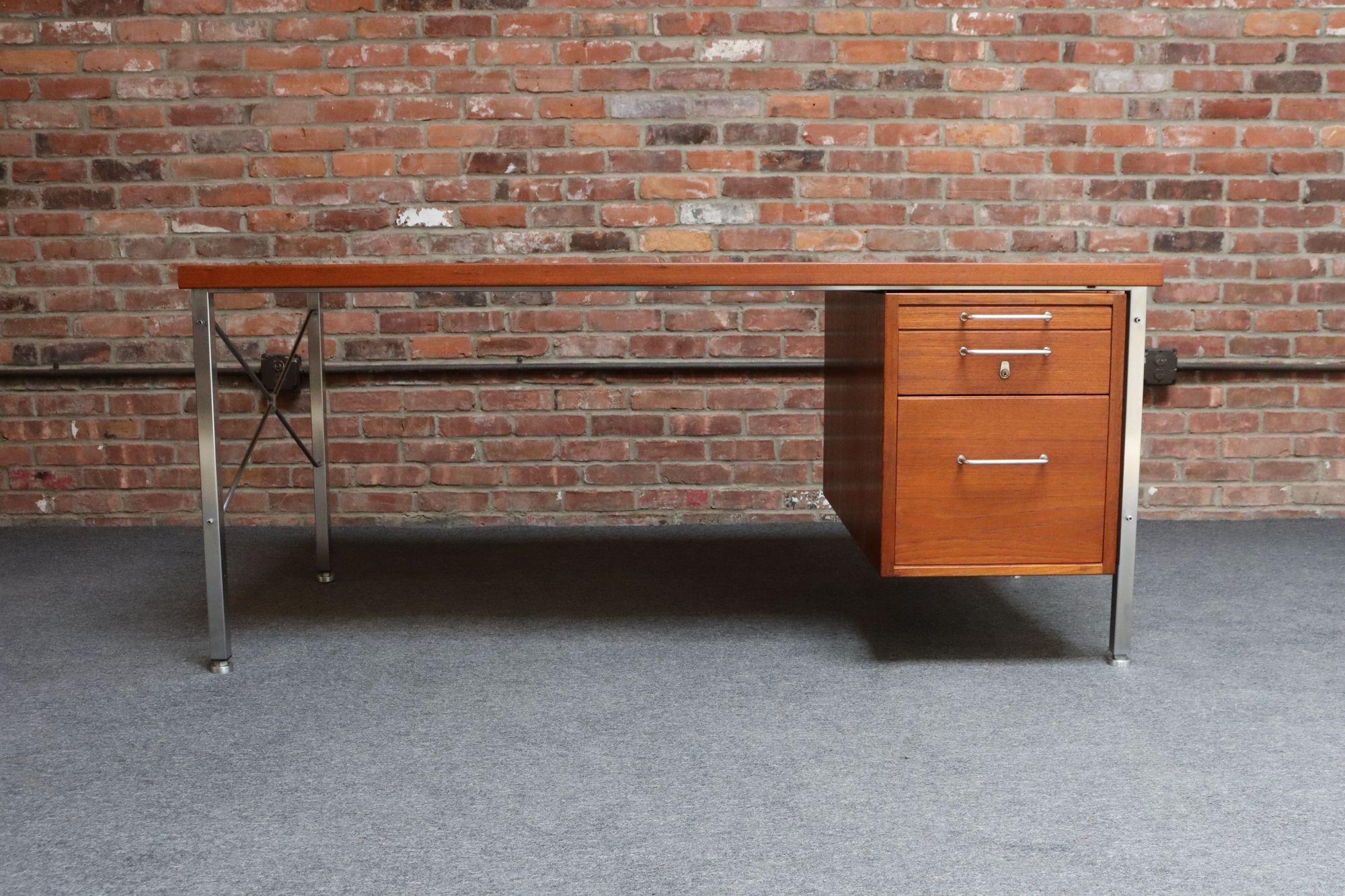 Moderner Chefschreibtisch (Kontour - Modell A 164 ) von Hans Wegner für Johannes Hansen, ca. 1965, Dänemark.
Er besteht aus einem Edelstahlrahmen, der eine massive Teakholzoberfläche und eine Reihe von drei schwalbenschwanzförmigen Schubladen trägt.