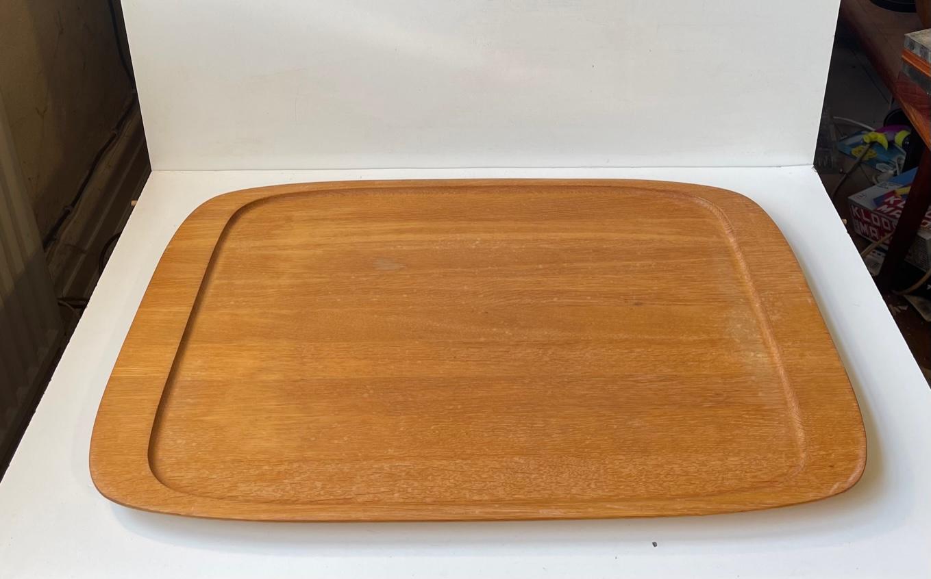 A large serving tray (60x43 cm) in solid oak. Fine subtle details and craftsmanship. It was made by Hundevad Møbler in Denmark circa 1970 and originally came along with a coffee table where it was suspended underneath. This tray can easily contain