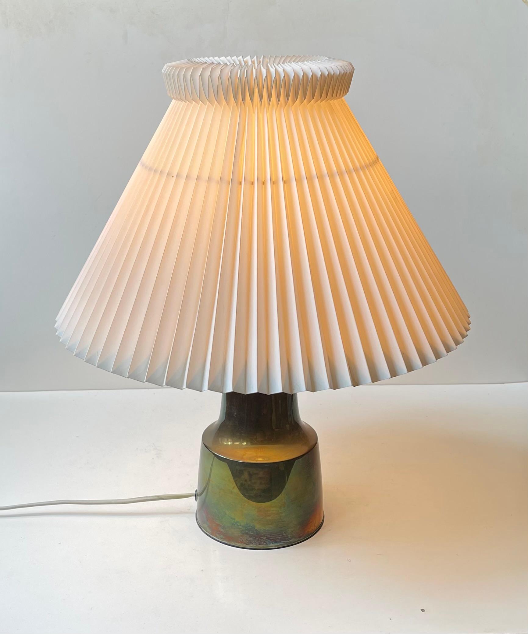 A pair of incredibly rare table lights designed by the Danish Silversmith Hans Bunde. Original undisturbed rainbow-like patina to the solid brass bodies. They come fitted with fluted period Le Klint shades and original sockets with pin on/off