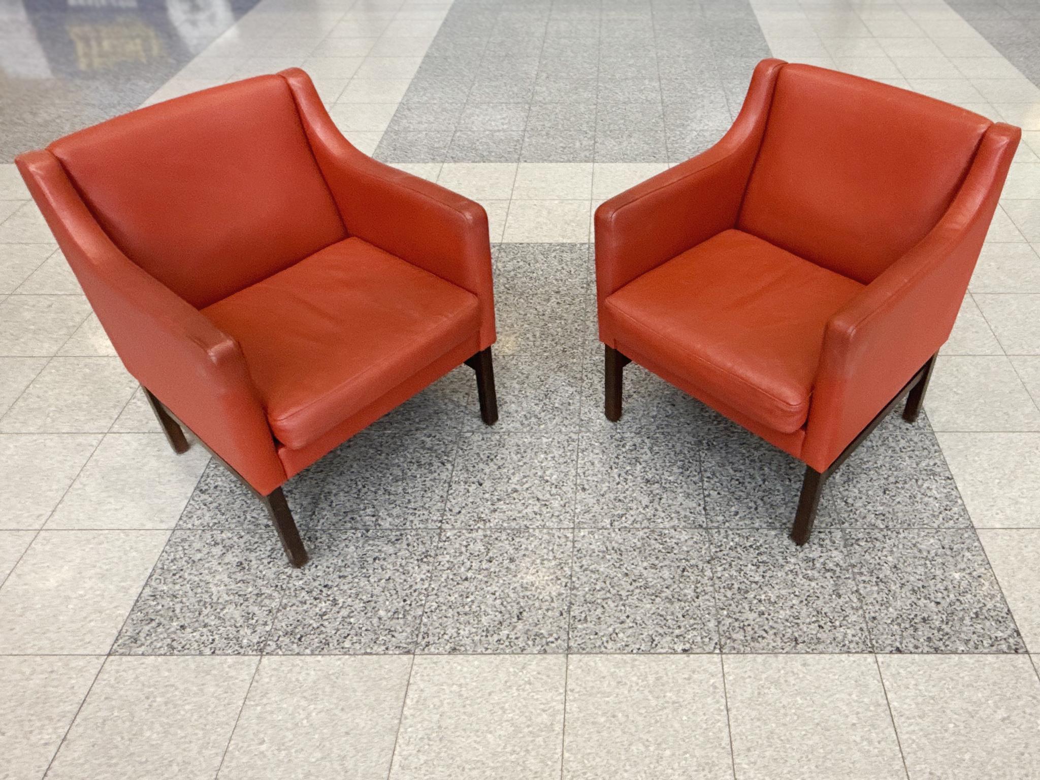 These Børge Mogensen-style lounge chairs were made in Denmark in the 1960s. They have red-orange leather upholstery and beech wood frame. Similar to Mogensen's designs, these chairs feature smooth lines that curve and soften at the corners. The