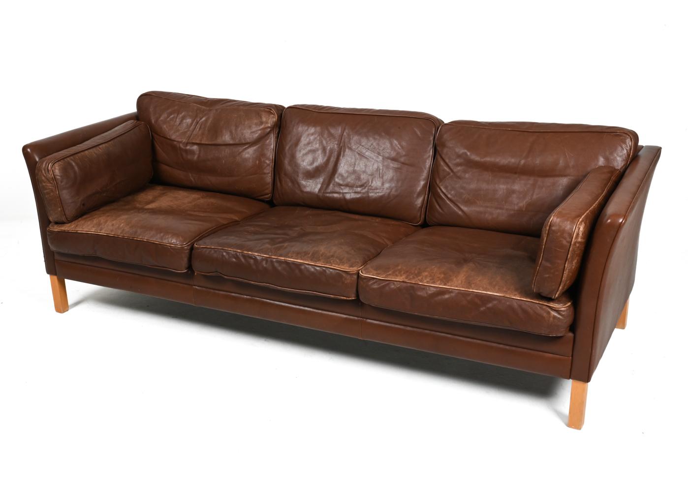 Introducing a Danish Modern masterpiece by Mogens Hansen – a three-seat sofa that effortlessly marries comfort with timeless Mid-Century design. Crafted in the Late 20th Century, this sofa boasts luxurious chocolate brown leather upholstery which