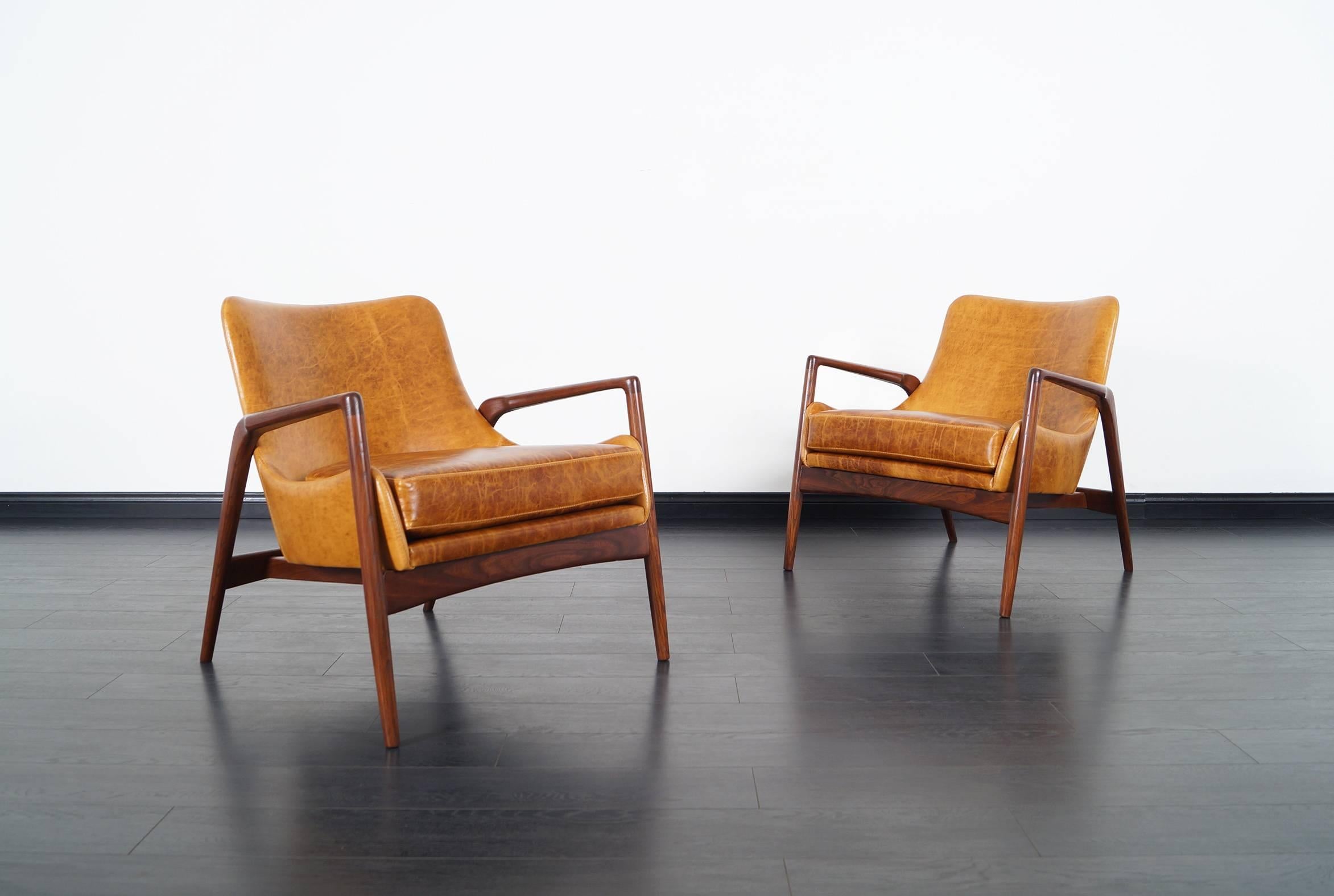 Stunning pair of Danish leather lounge chairs designed by Ib Kofod Larsen. The way the leather shell seat seems to be floating inside the wooden frame, gives the design an amazing feel from any angle.