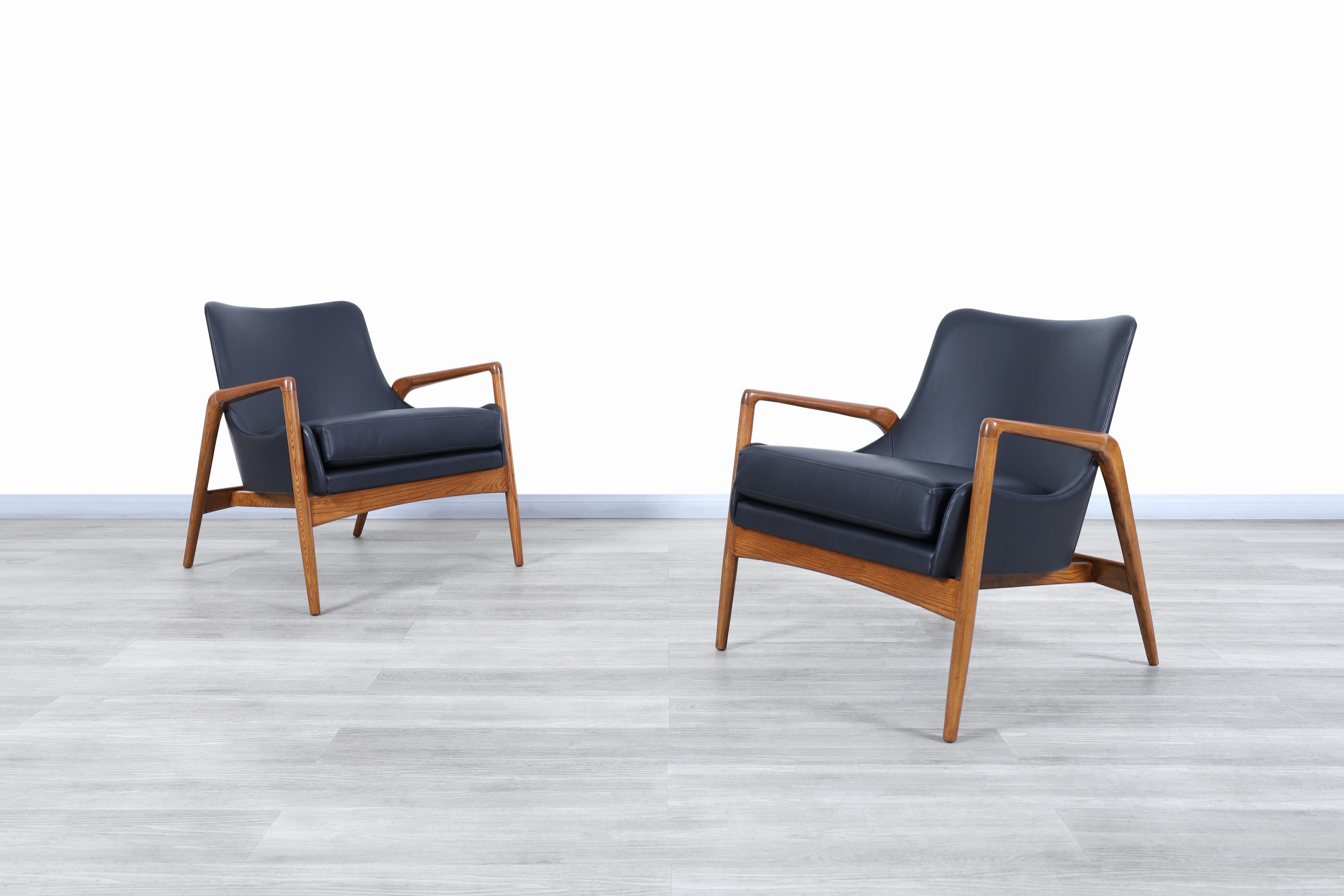 Wonderful Danish modern leather lounge chairs designed by Ib Kofod Larsen for Selig in Denmark, circa 1950s. The sculptural frames on these chairs are made of solid walnut stain. The well-crafted armrests and barrel shape design shows beautiful