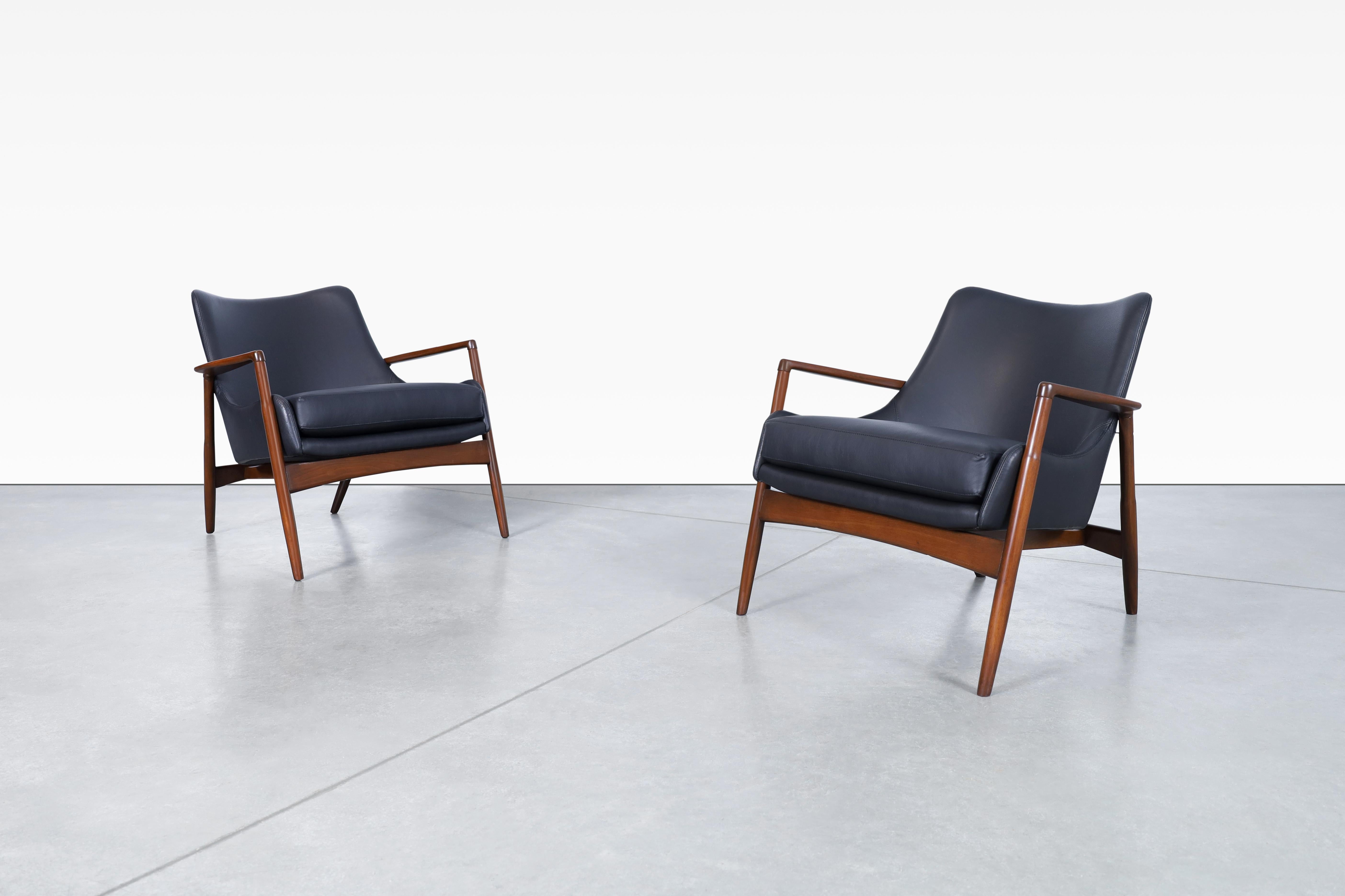 Wunderschöne moderne dänische Ledersessel von Ib Kofod Larsen für Selig in Dänemark, ca. 1950er Jahre. Die skulpturalen Rahmen dieser Stühle sind aus massivem, gebeiztem Nussbaumholz gefertigt. Die gut verarbeiteten Armlehnen und das tonnenförmige