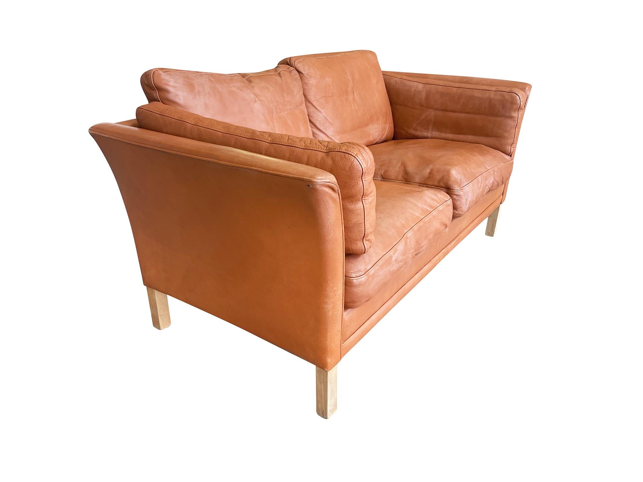 Midcentury Danish Modern settee by Mogens Hansen. The upholstery is a rich cognac leather. There are 6 separate cushions that make up the seating, backrest, and sides. The legs are maple wood.

Additional images are available upon