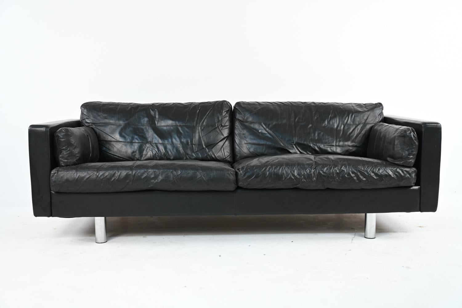 This luxurious seating suite consists of a three-seat sofa and two-seat settee. Produced by Friis Møbler, this classic Erik Jørgensen design features substantial cushions and a low-profile back over cylindrical aluminum legs for a stately and Modern
