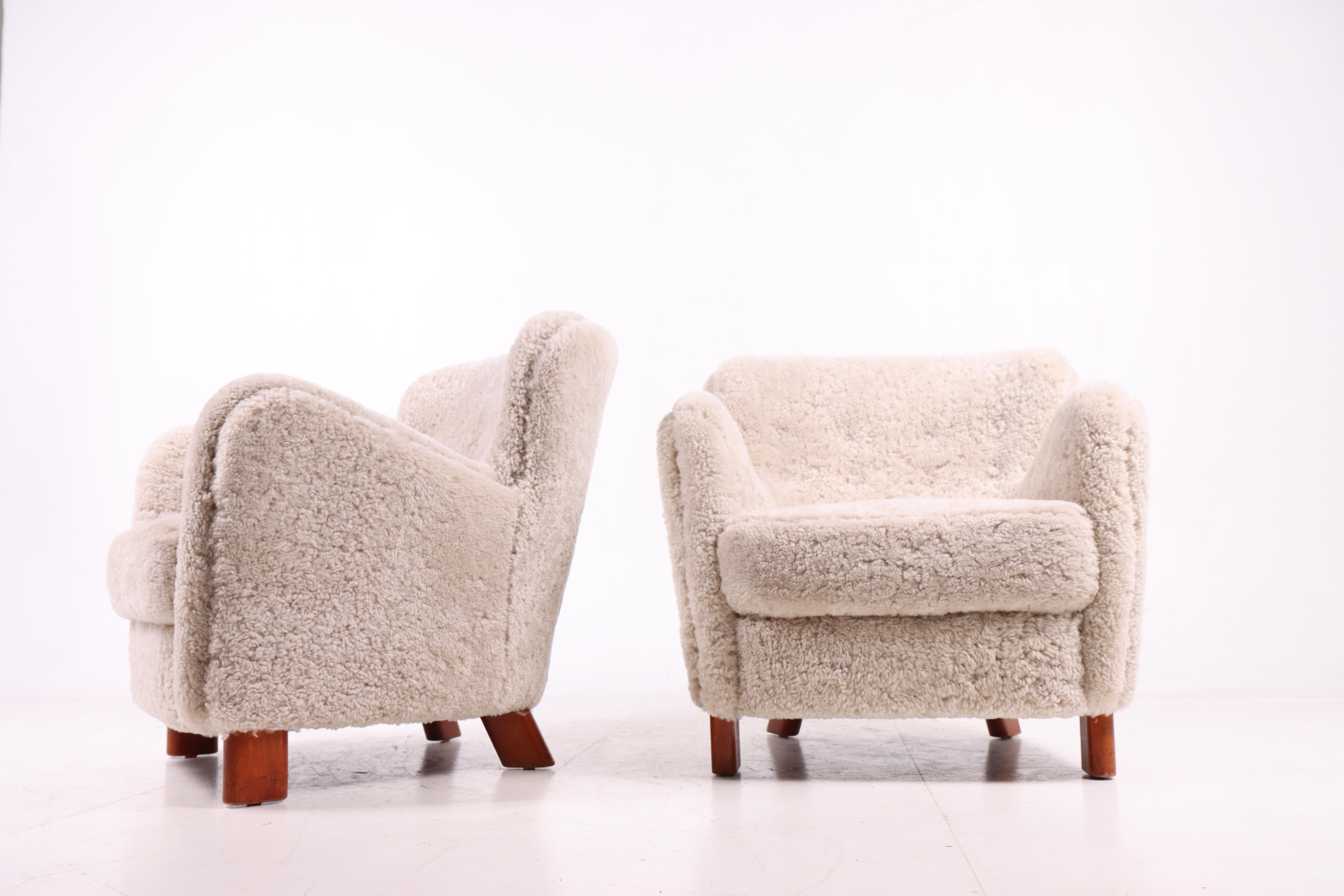 Magnifique paire de chaises longues originales de Fritz Hansen, modèle 1669, conçues et produites au Danemark dans les années 1950. Les chaises ont été nouvellement recouvertes d'une peau de mouton néo-zélandaise exclusive, ce qui leur confère un