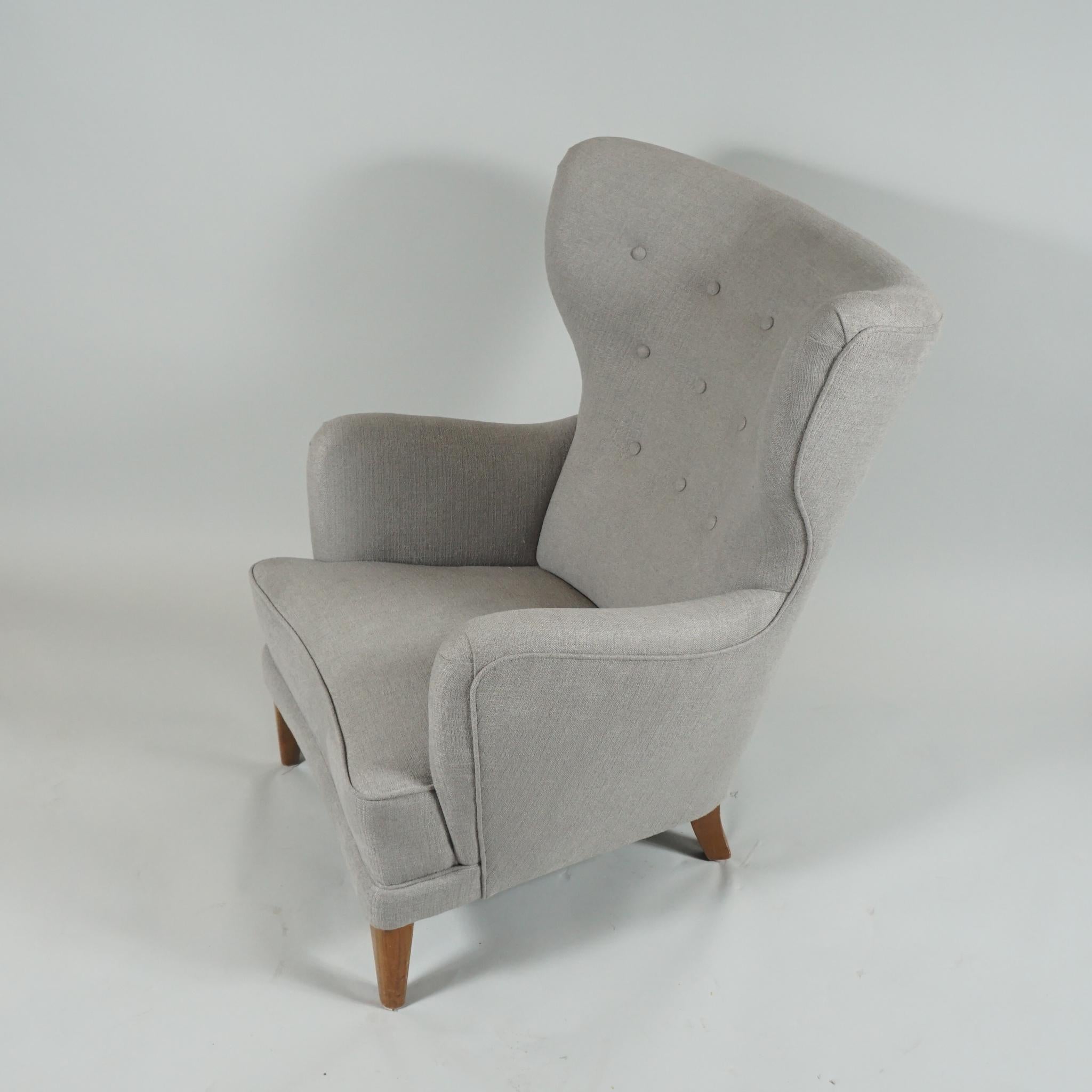 Handsome Danish modern lounge chair with high winged-back and generous curved arms, 
newly reupholstered in a soft grey wool fabric, legs in beech.