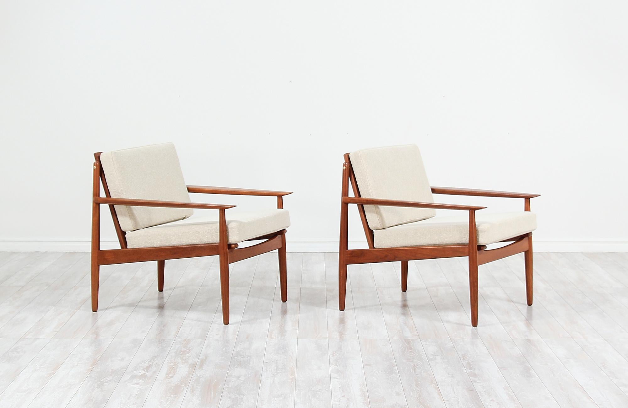 Pair of elegant modern lounge chairs designed by Svend Åge Eriksen and manufactured in Denmark by Glostrup Møbelfabrik, circa 1960s. This beautiful pair of lounge chairs feature a solid teak wood frame and sculpted armrests with organic shapes