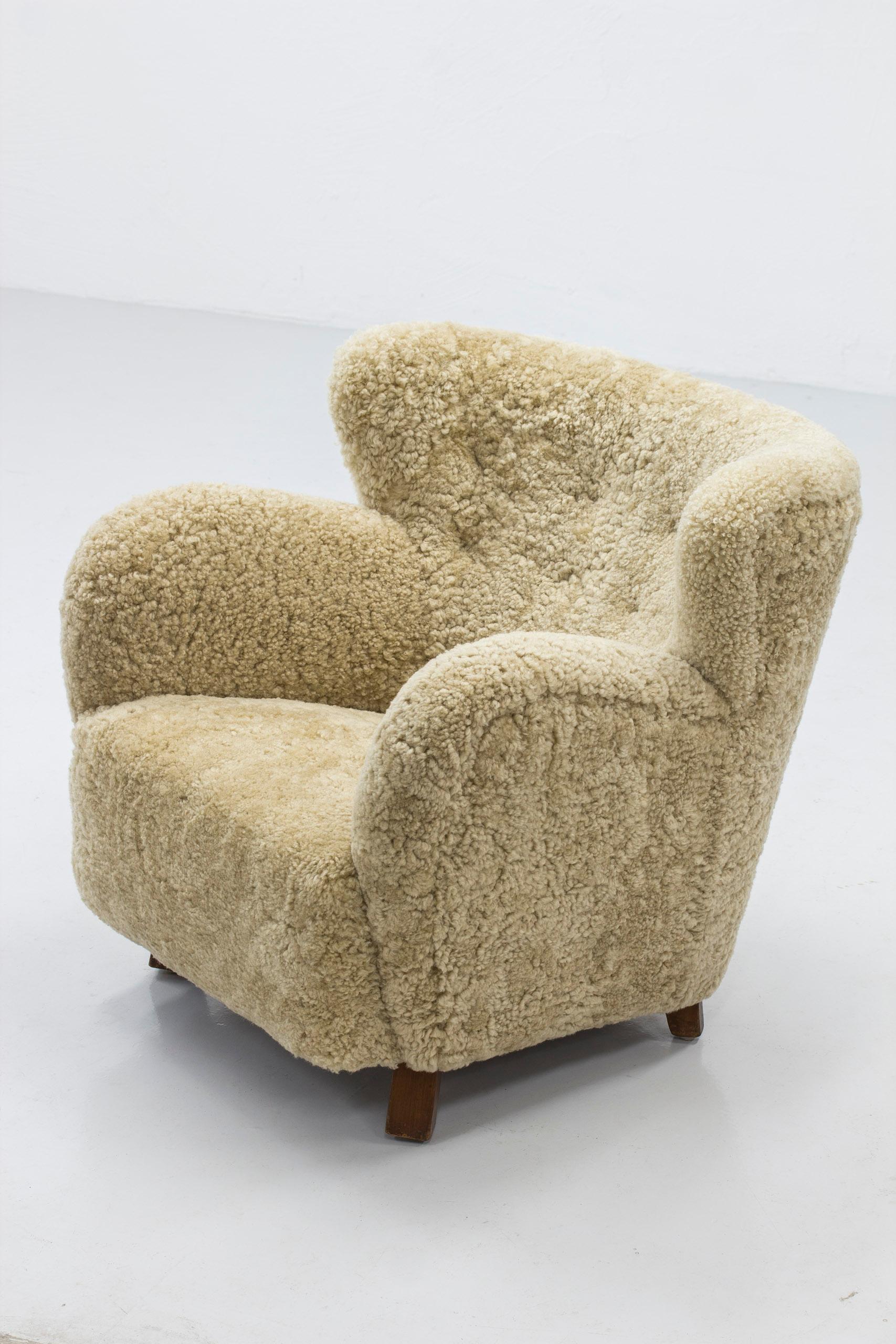 Danish modern low back wing chair made by a Danish craftsman. Excellent quality in shape and production. Low and comfortable design. Legs made from solid maple wood. New upholstery in beige sheep skin of great quality. Very good condition with very