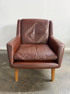 Silla baja danesa moderna de cuero marrón con base curvada de roble