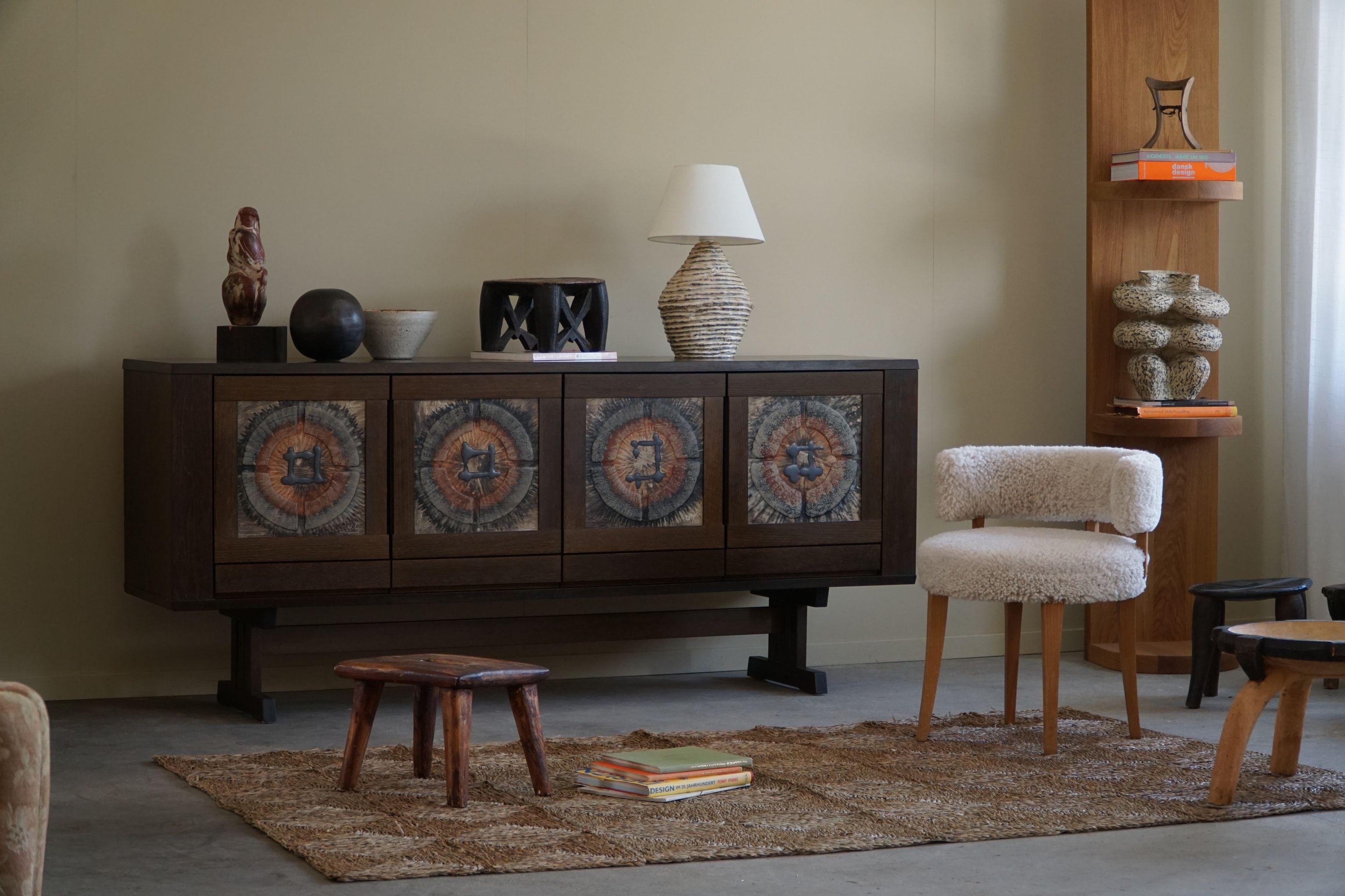 Experience the timeless elegance and craftsmanship of Danish Modern design with this exquisite low sideboard by Skovby, created during the 1970s. Crafted from stained oak and adorned with beautifully textured ceramic tiles, this piece blends form